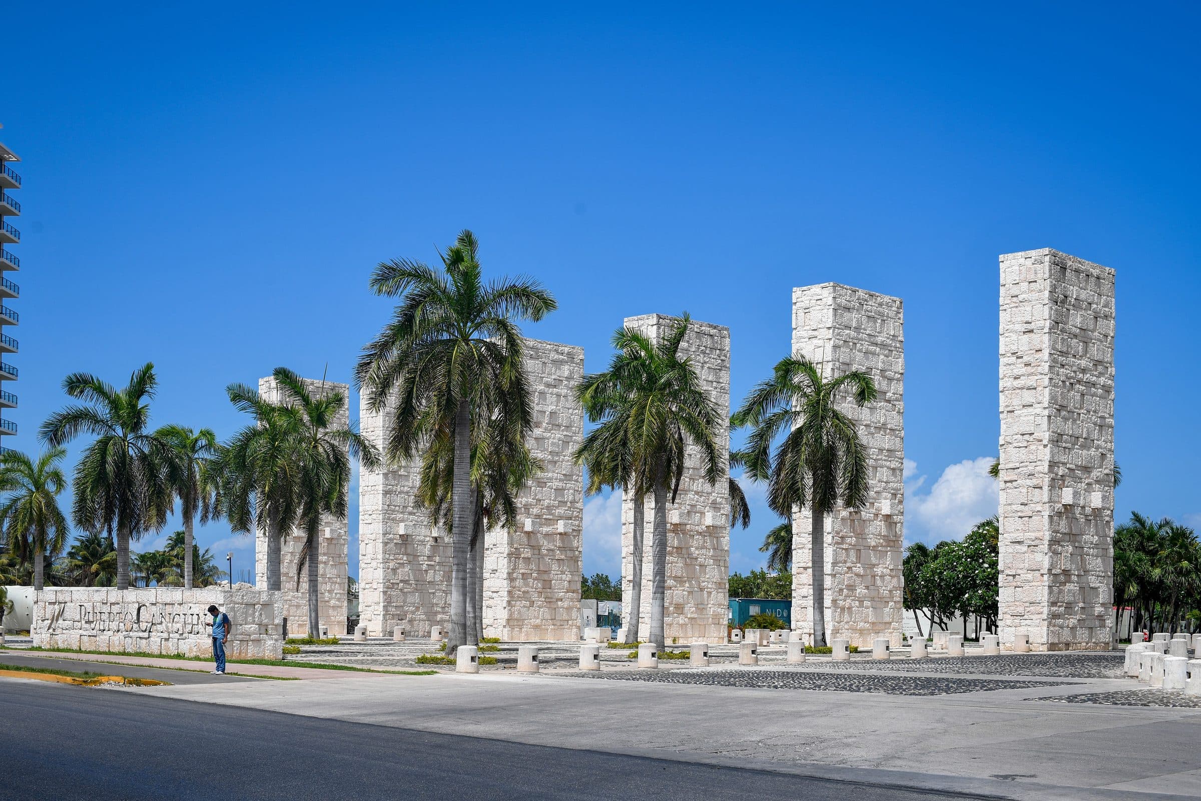 Colunas de pedra e palmeiras em área urbana ensolarada de Cancún, no México