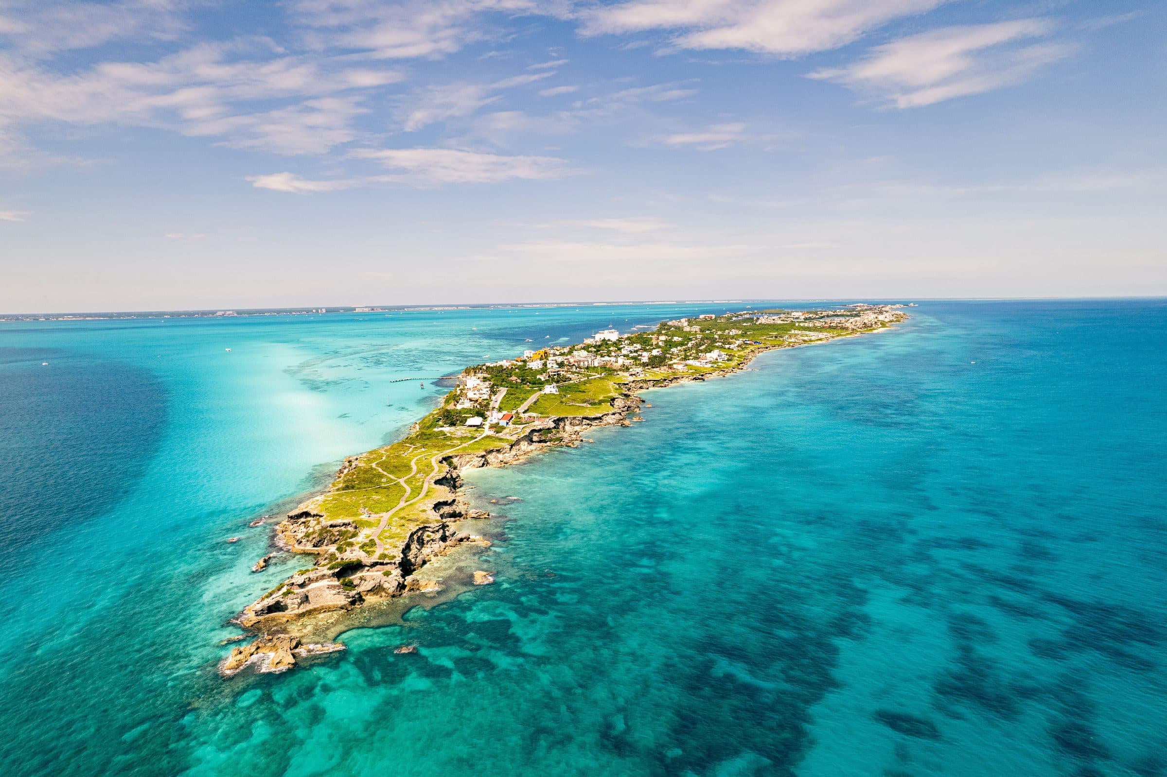 Vista aérea de Isla Mujeres cercada por águas azul-turquesa e vegetação no Mar do Caribe