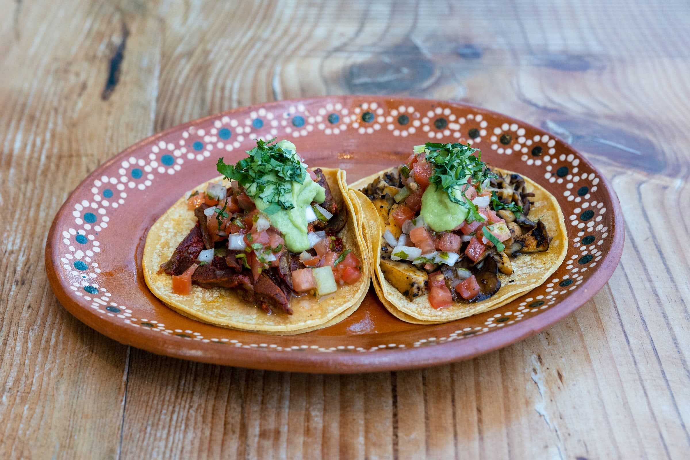 Close-up de tacos mexicanos com acompanhamentos sobre uma mesa de madeira