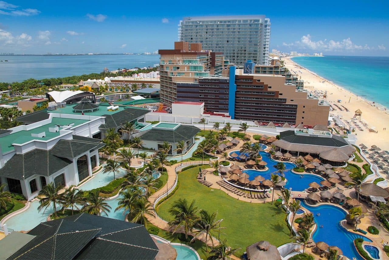 Vista de praia com piscina de hotel e edifícios à beira-mar em Cancún, México