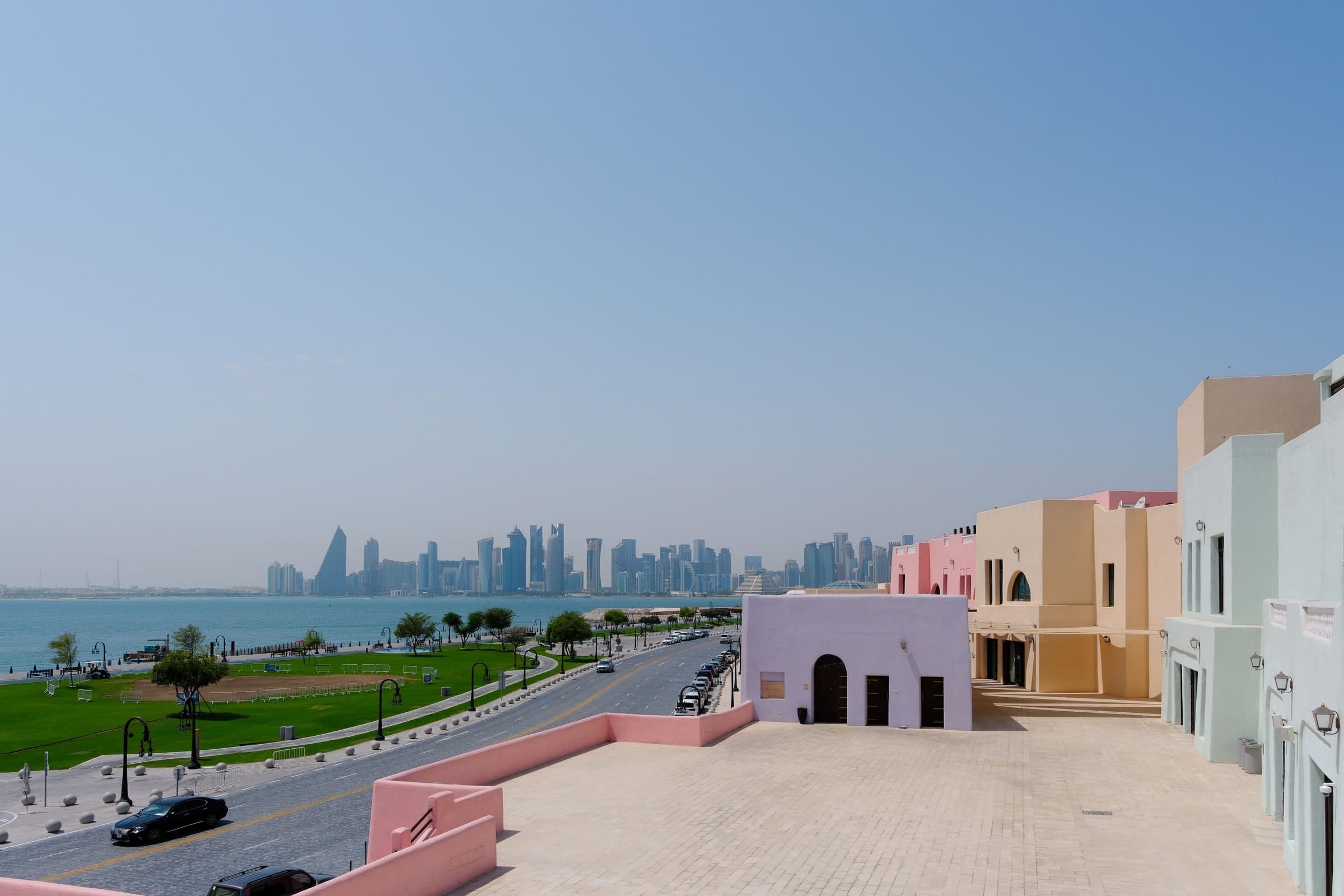 Vista do horizonte de Doha com edifícios em tons pastel ao longo da orla