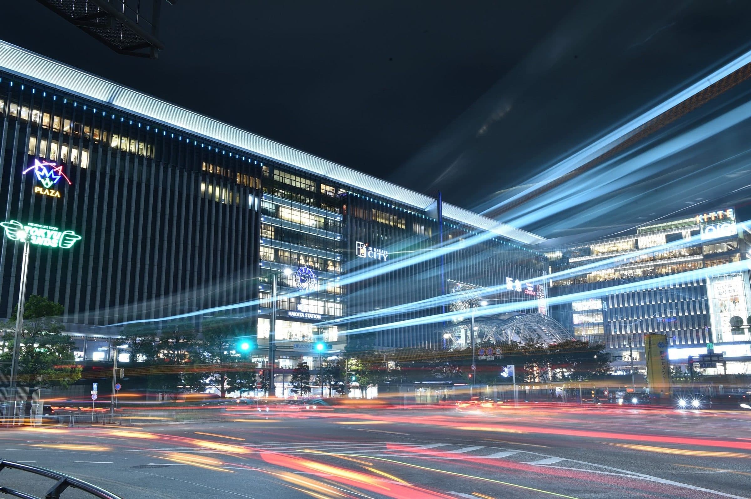 Paisagem urbana noturna de Fukuoka com arquitetura moderna e rastros de luz