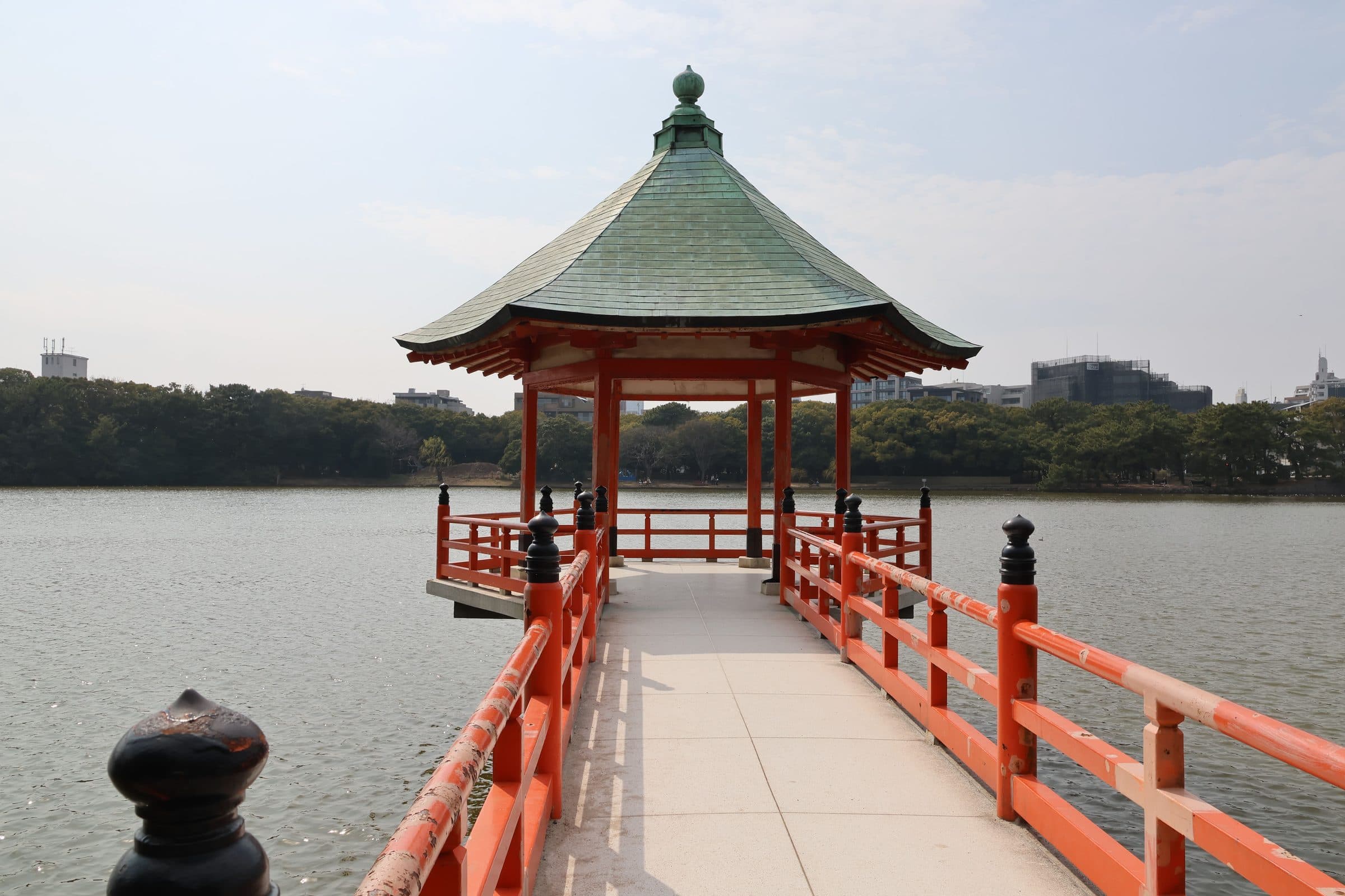 Pagode tradicional japonês com grades vermelhas à beira de um lago