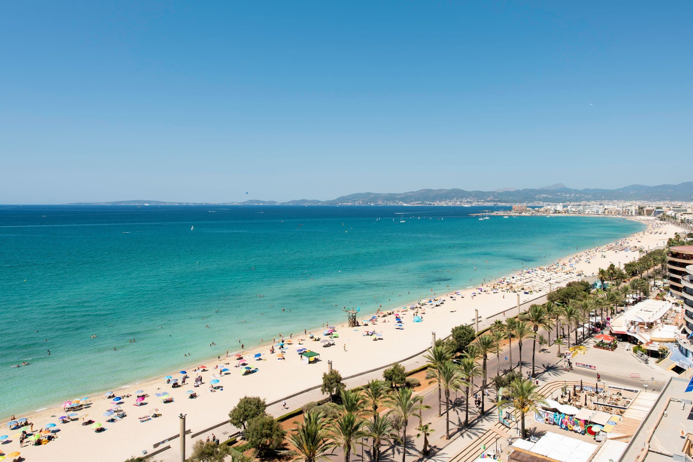 Vista aérea da praia de Palma de Mallorca com mar de águas claras e banhistas na areia