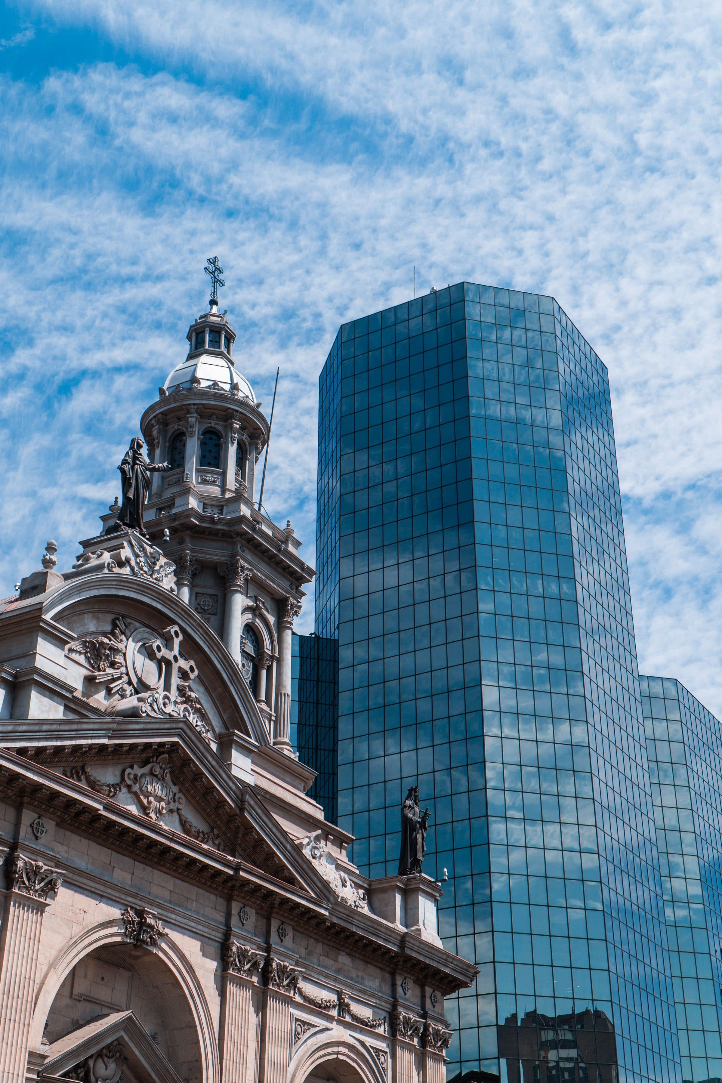 Contraste entre arquitetura histórica e arranha-céu moderno de vidro em Santiago, Chile