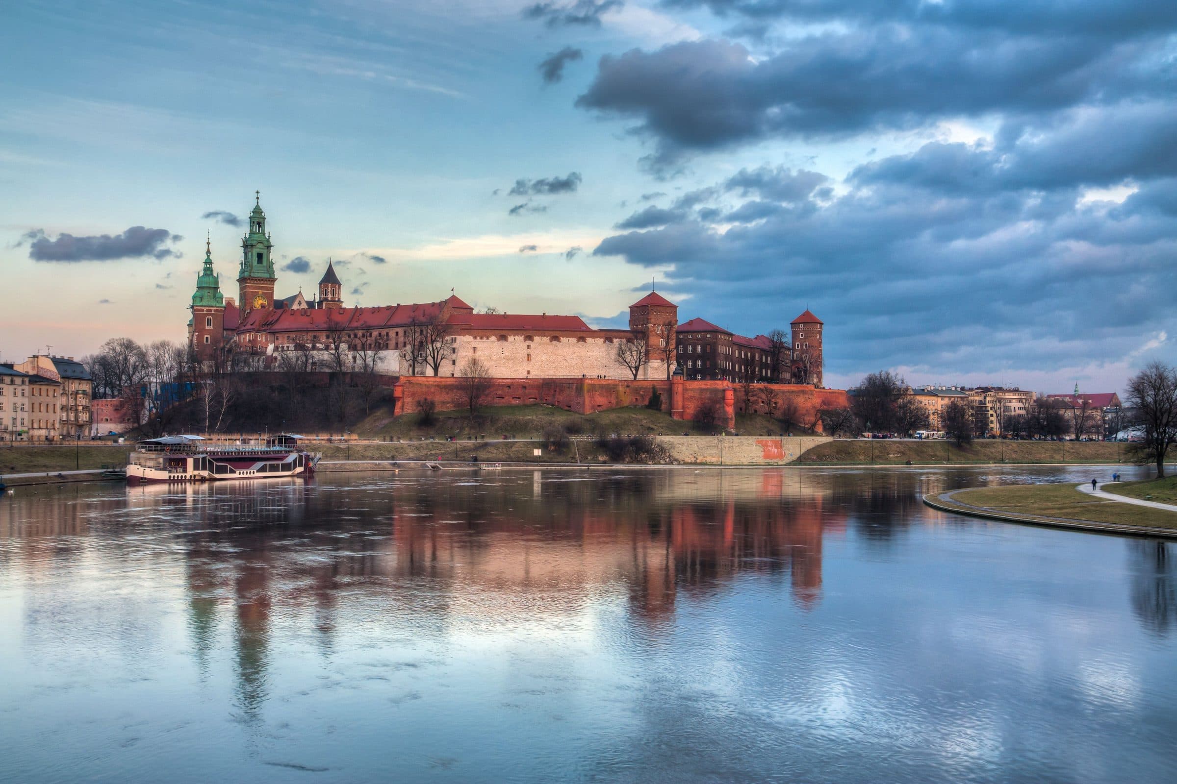 Castelo de Wawel refletido no Rio Vistula ao pôr do sol em Kraków