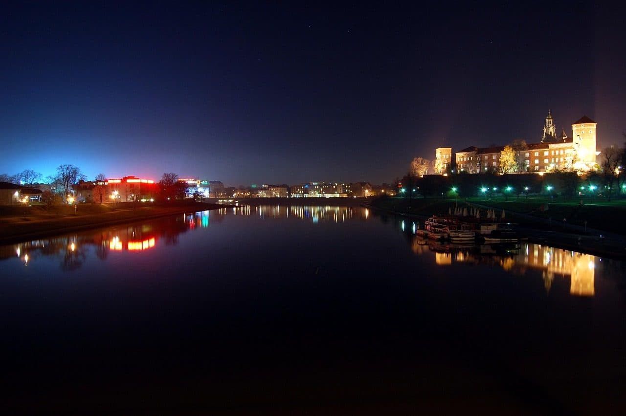 Vista noturna do Castelo de Wawel iluminado às margens do rio Vístula em Kraków