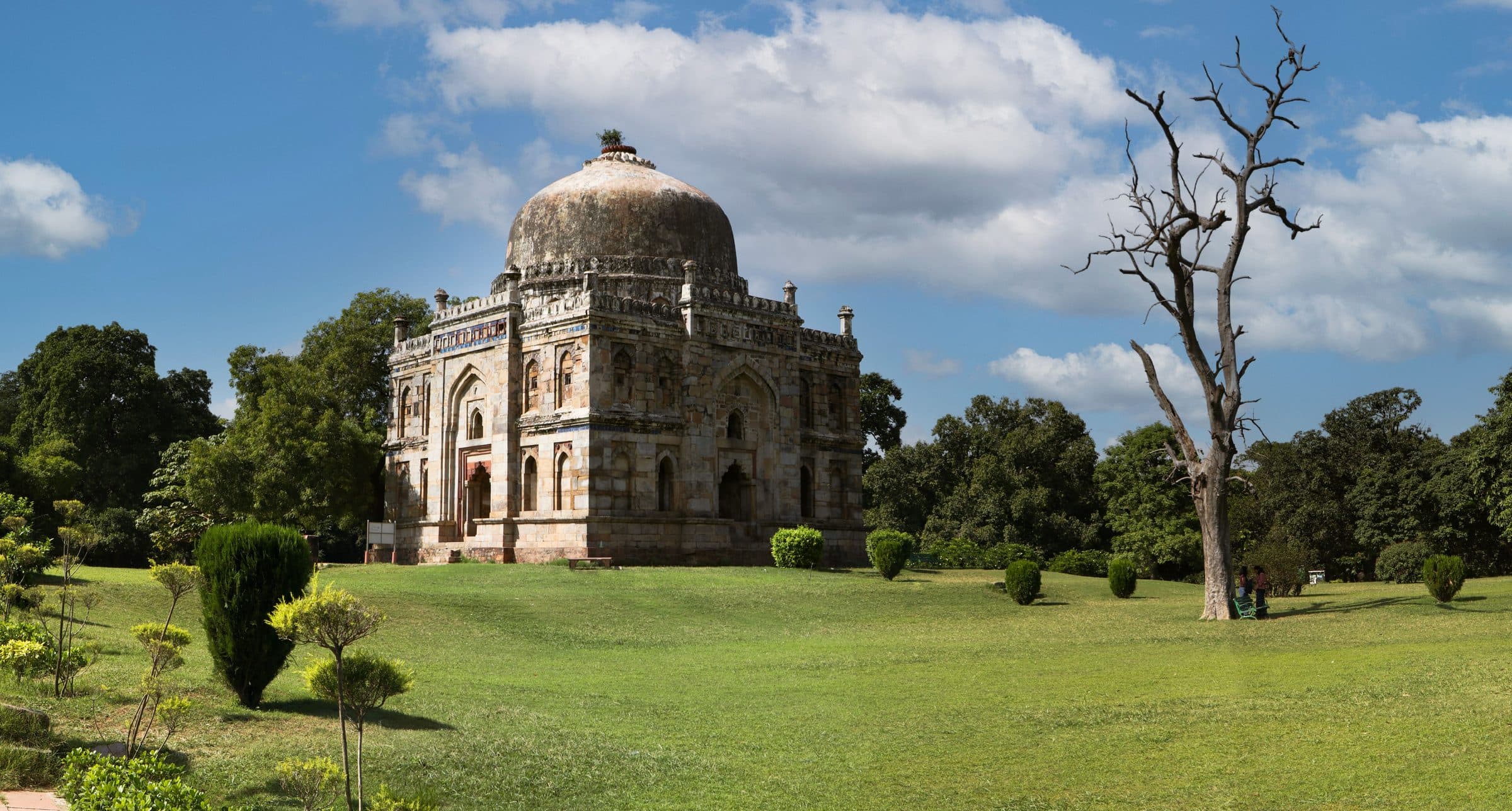 Tumba histórica de Shish Gumbad cercada por jardins e céu azul em Nova Délhi