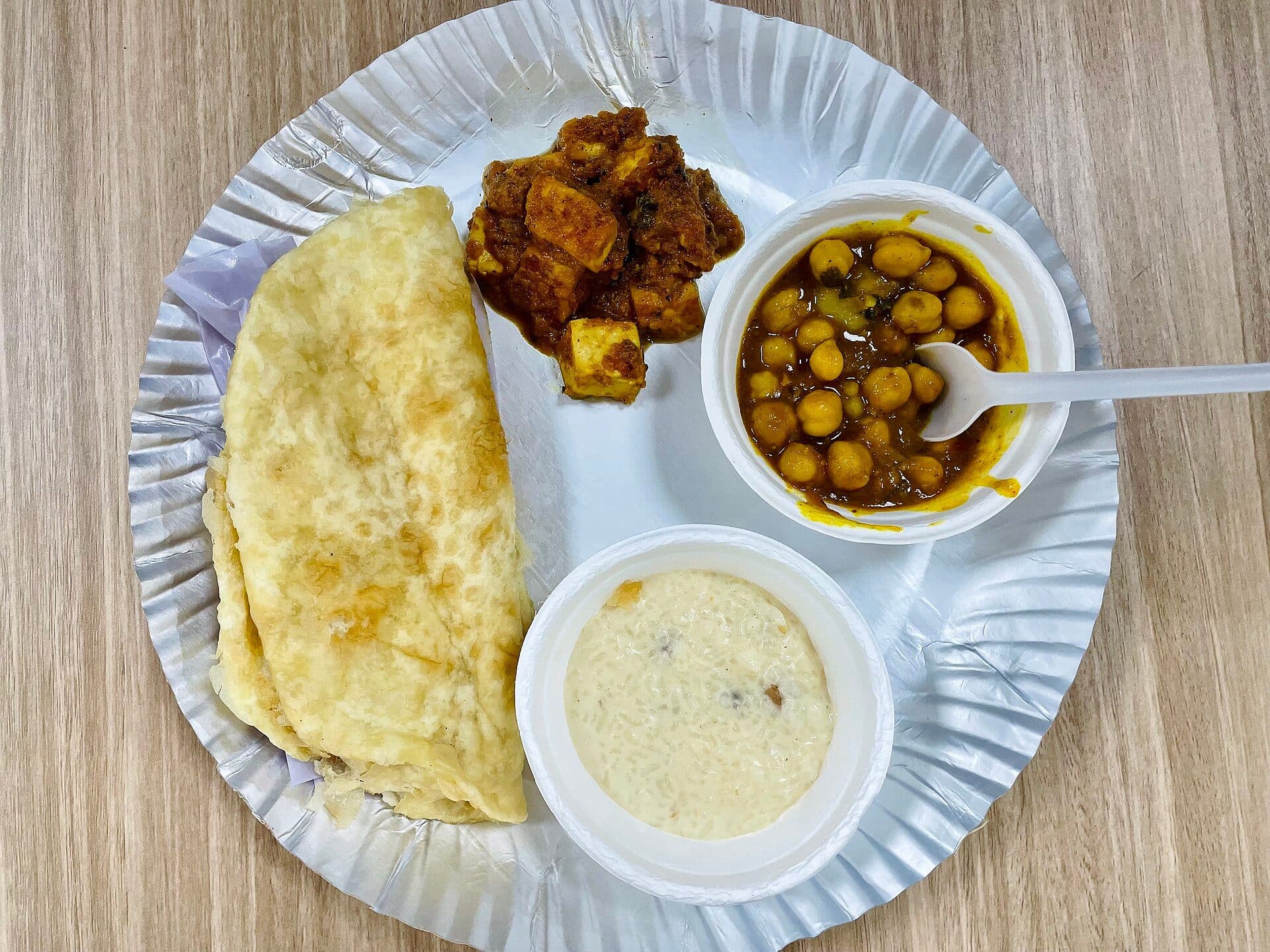 Porção de chole bhature acompanhada de paneer masala e sobremesa kheer