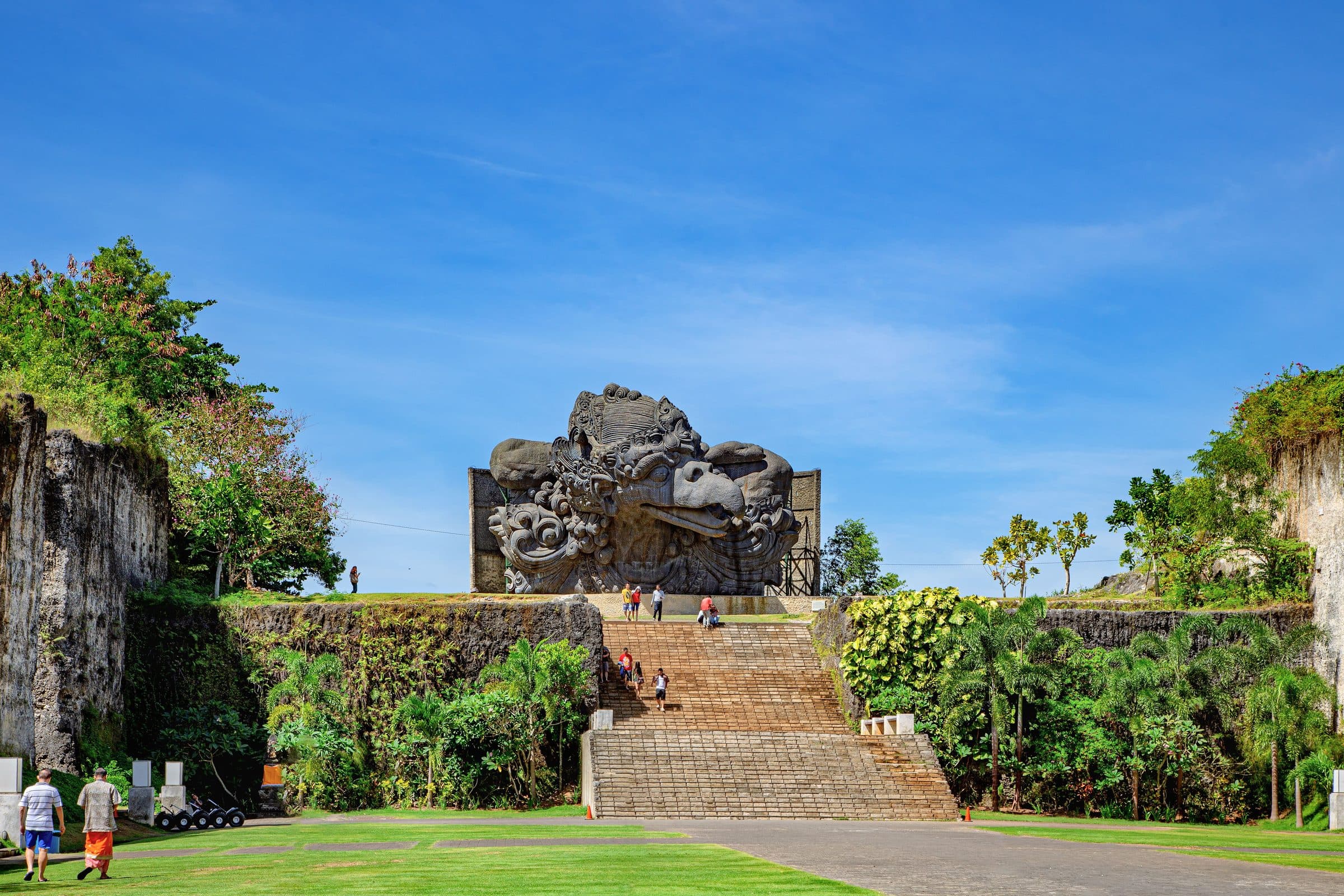 Visitantes passeando pelo Garuda Wisnu Kencana Cultural Park em Bali sob céu azul