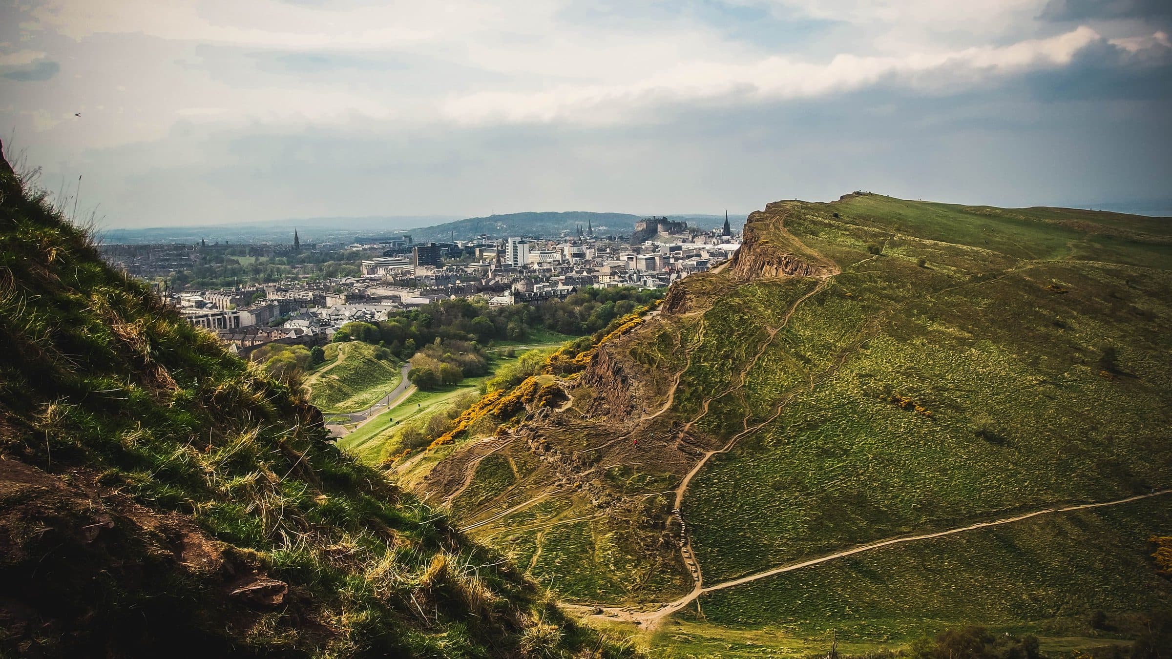 Vista da cidade de Edinburgh a partir do Arthur's Seat, com paisagens verdes e edifícios históricos