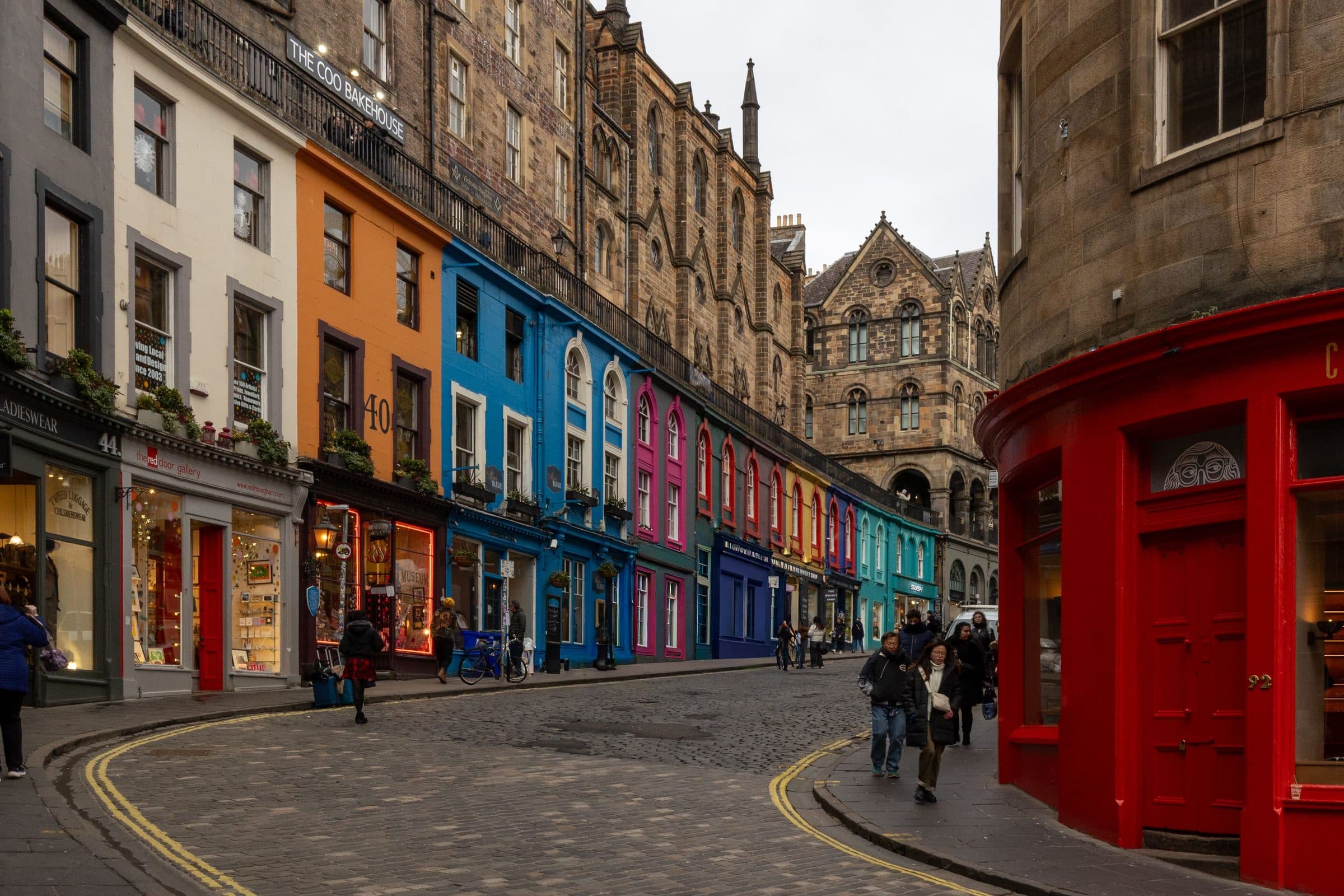 Rua de Edimburgo com lojas coloridas e prédios de arquitetura histórica