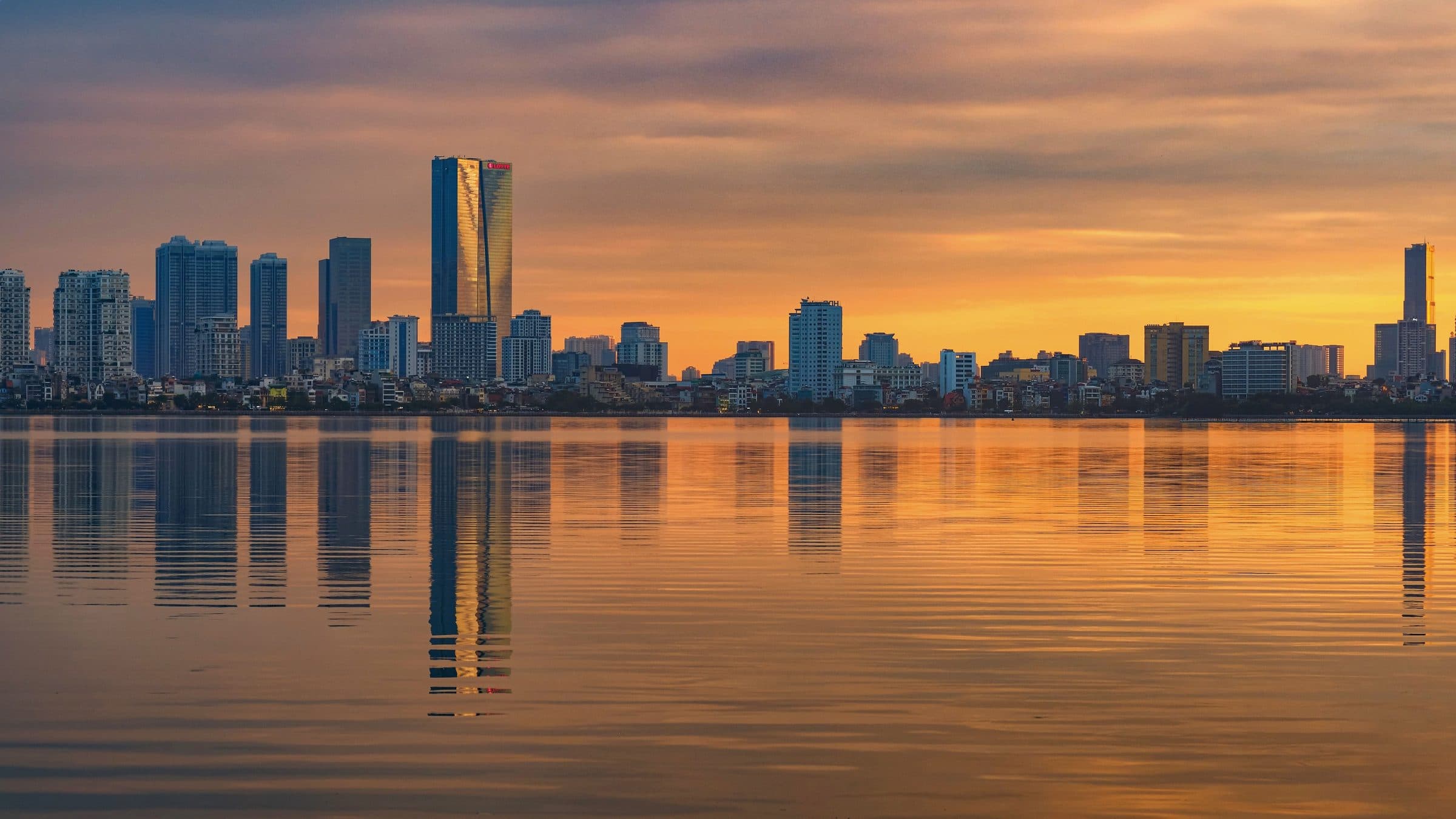 Horizonte urbano de Hanói refletido na água durante o pôr do sol no Vietnã