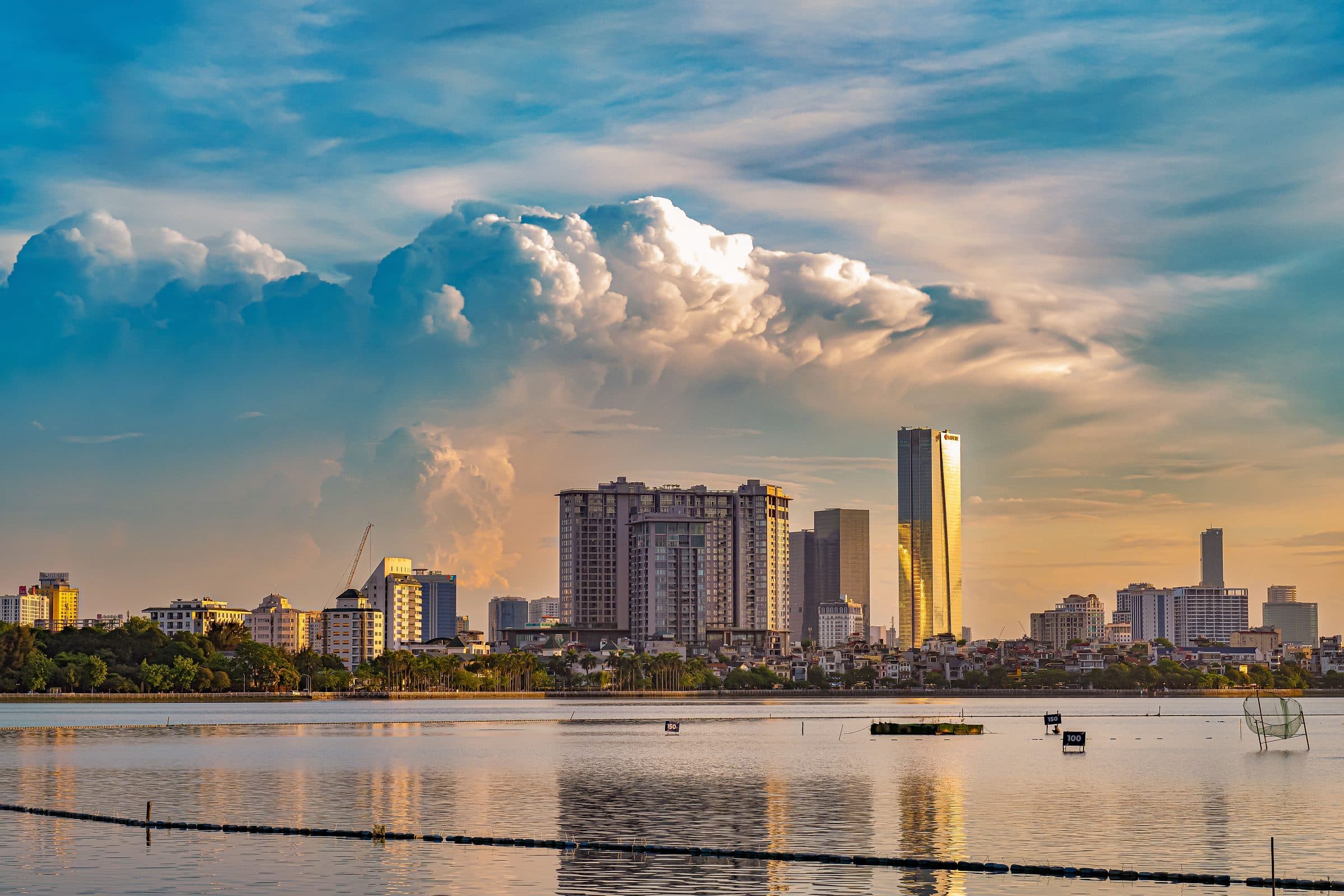 Pôr do sol sobre os edifícios de Hanói refletido nas águas calmas do rio