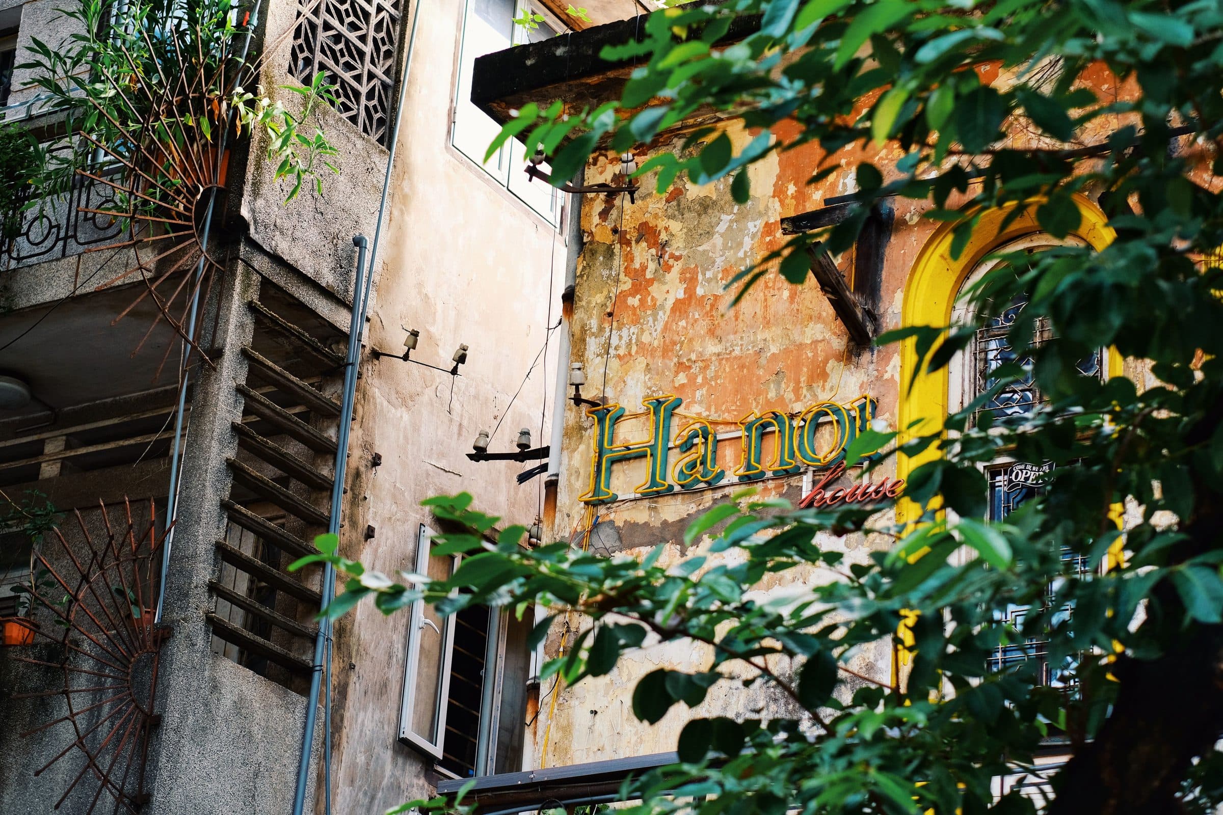 Prédio urbano rústico em Hanói com vegetação densa e placas na fachada