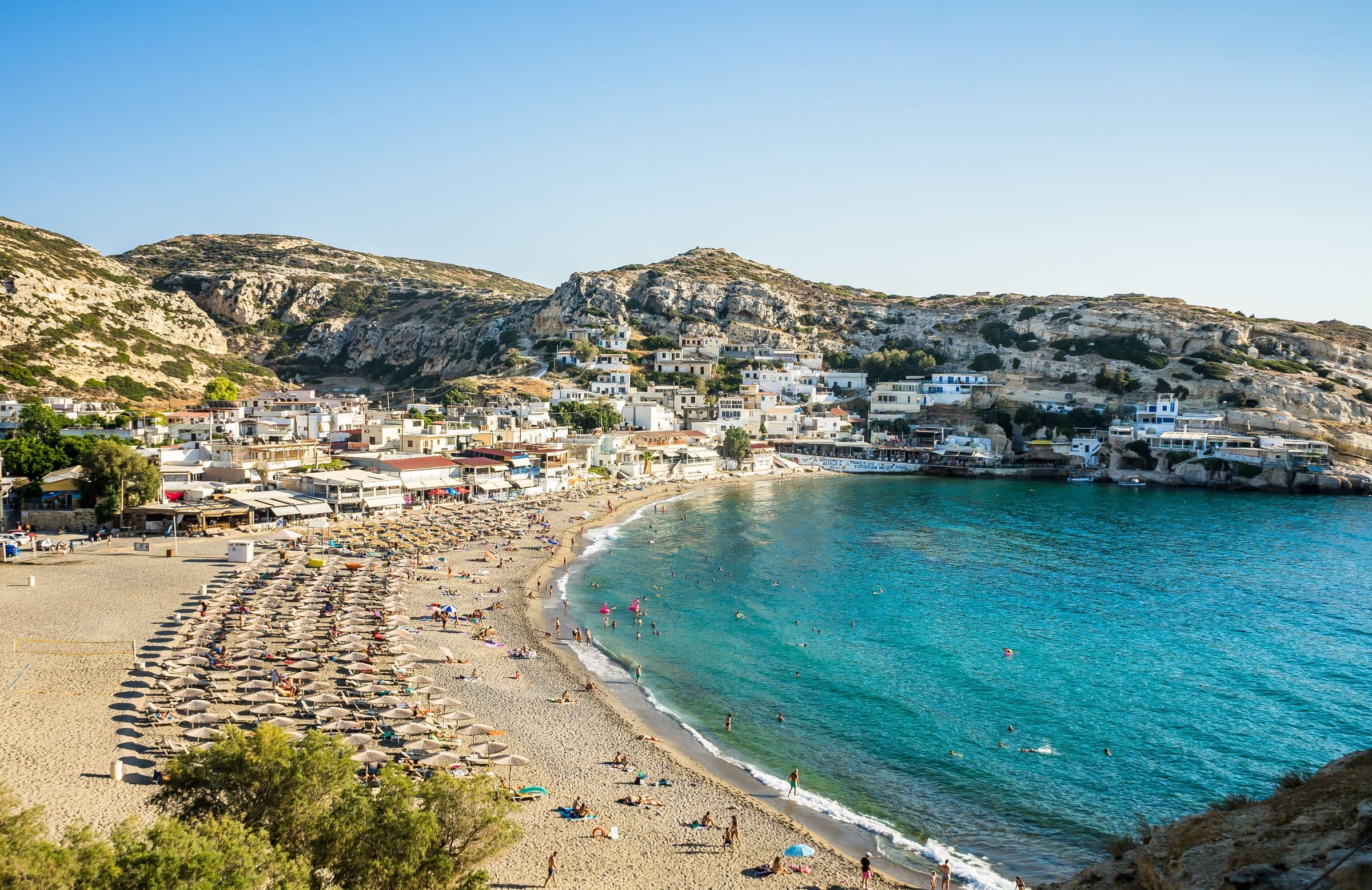 Pessoas tomando sol e nadando na Praia de Matala, em Creta, na Grécia