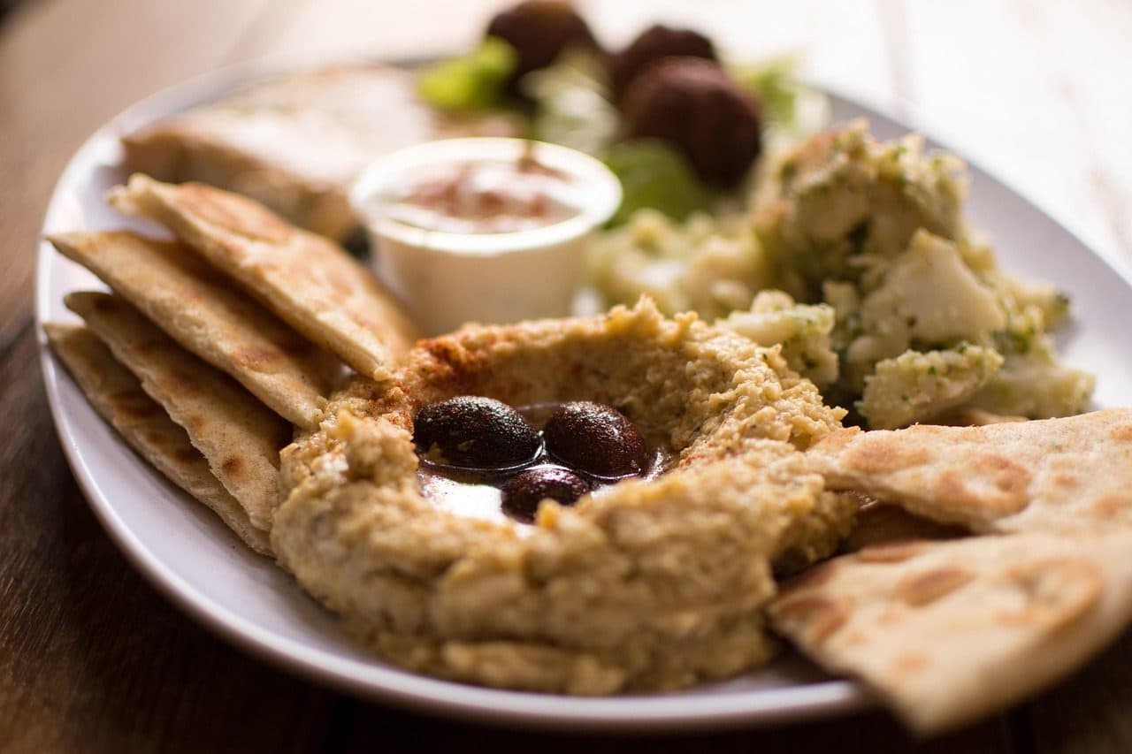 Mesa com porções de homus, falafel e aperitivos tradicionais