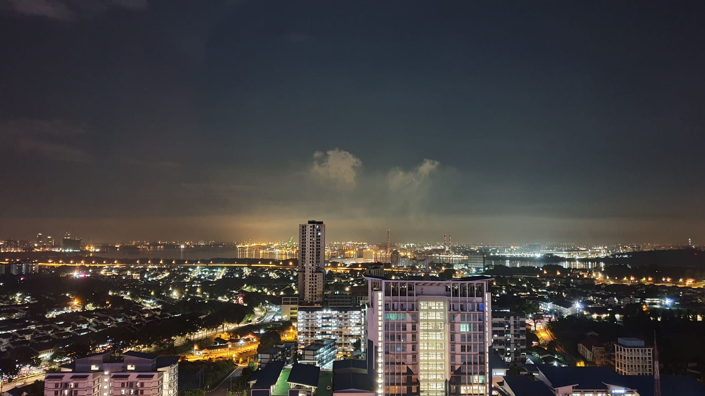 Vista noturna da cidade de Johor Bahru com prédios iluminados e céu limpo