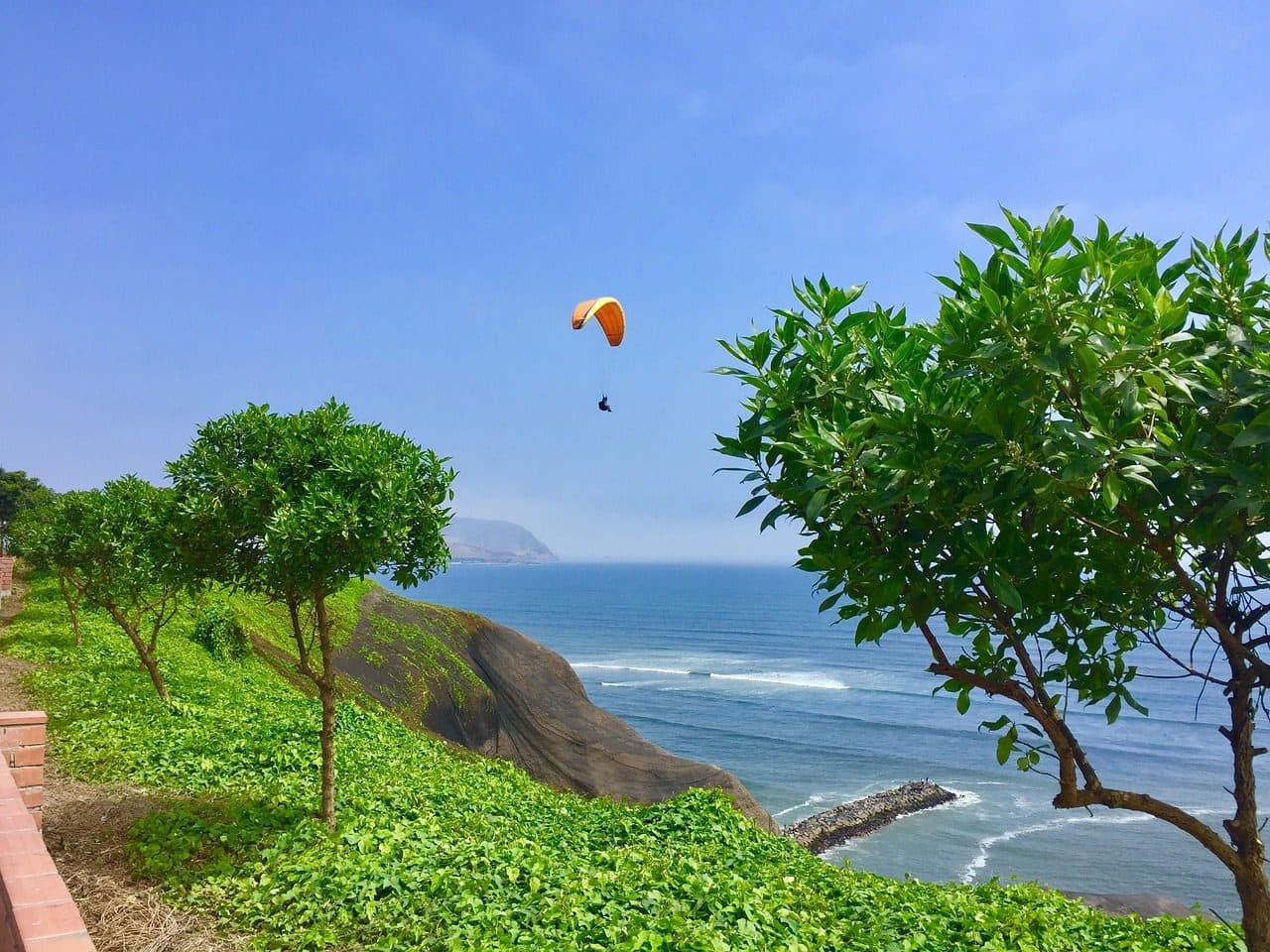 Pessoa praticando voo de parapente no céu sobre Miraflores em Lima, Peru