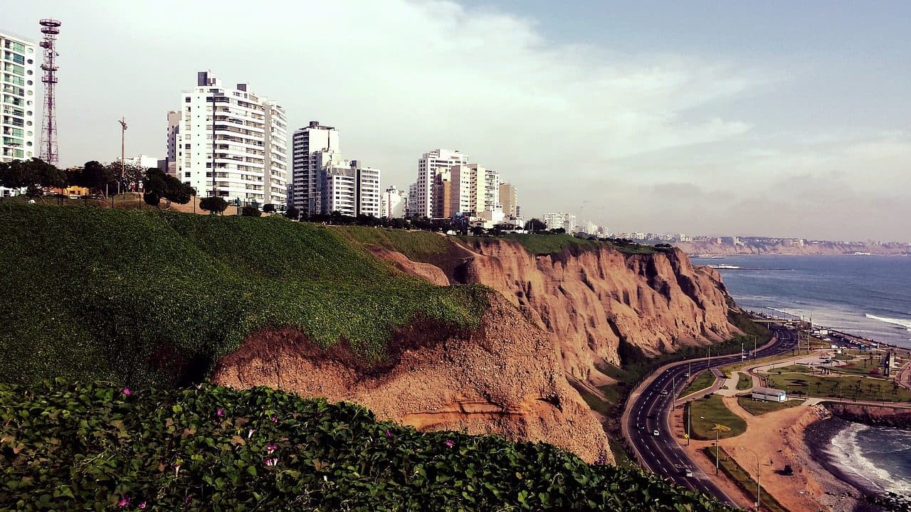 Vista da costa do Pacífico em Miraflores, Lima, com falésias, estrada sinuosa e edifícios à beira-mar