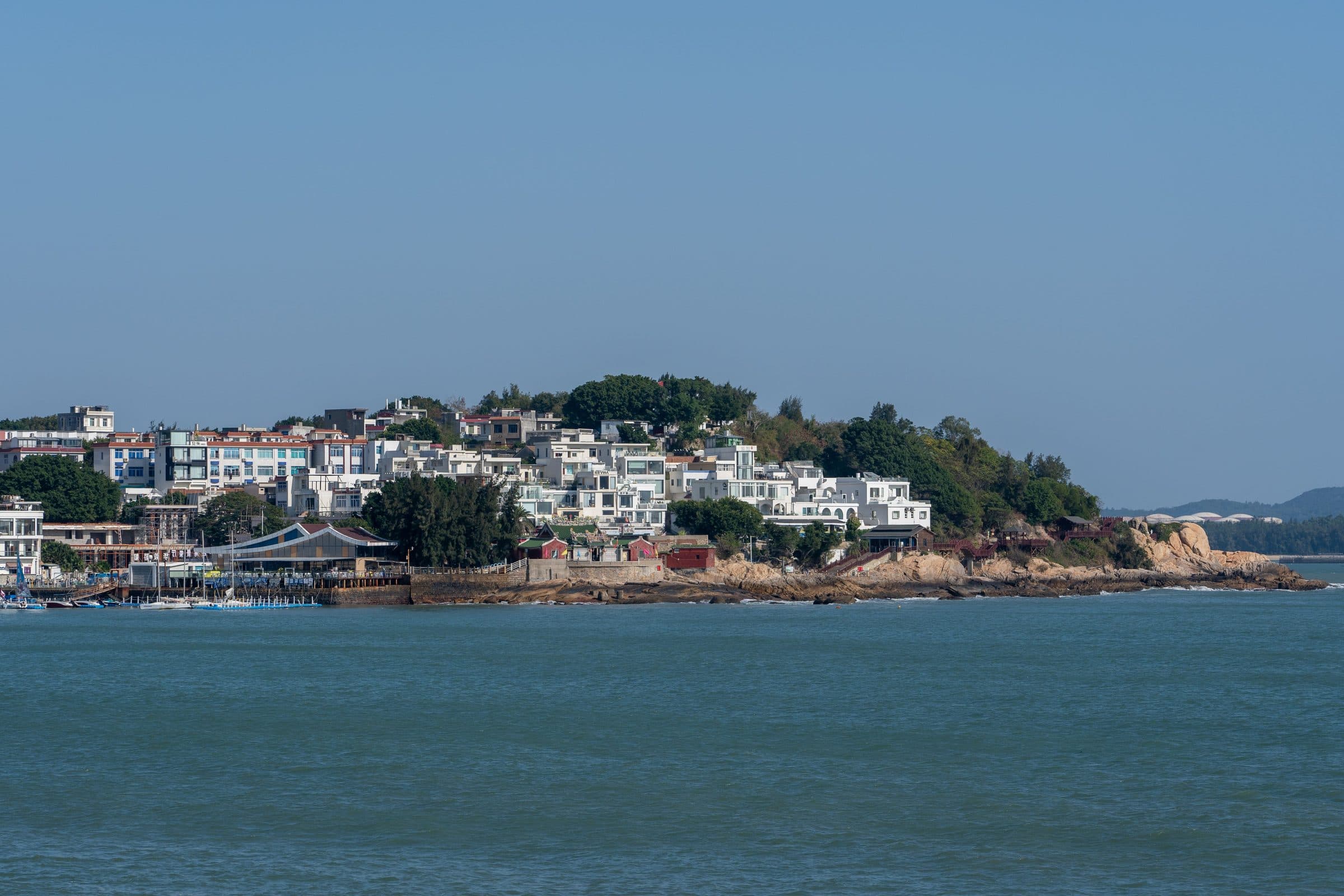 Cidade litorânea com construções brancas à beira do mar sob céu azul