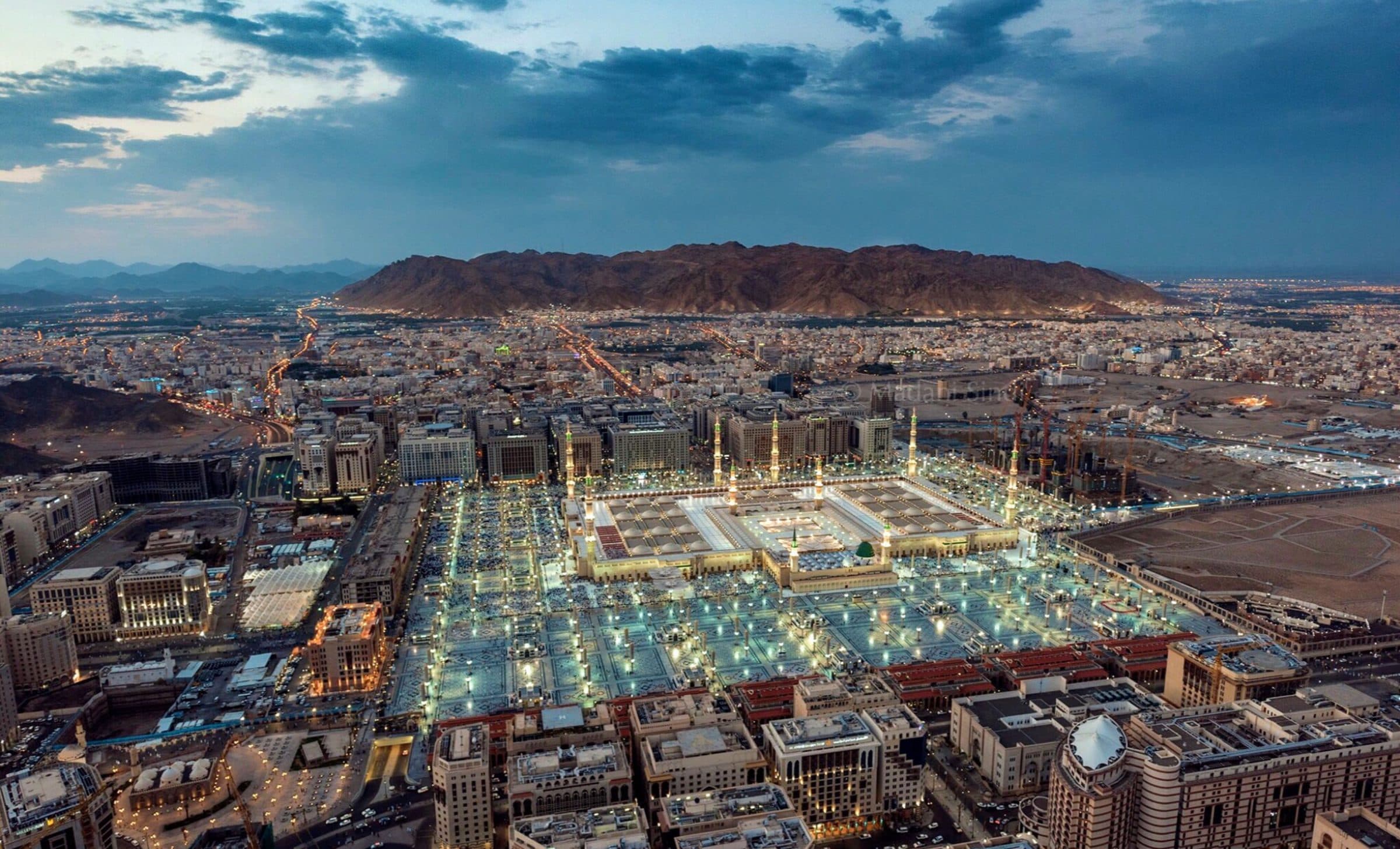 Vista aérea da mesquita Al-Masjid an-Nabawi iluminada ao entardecer em Medina