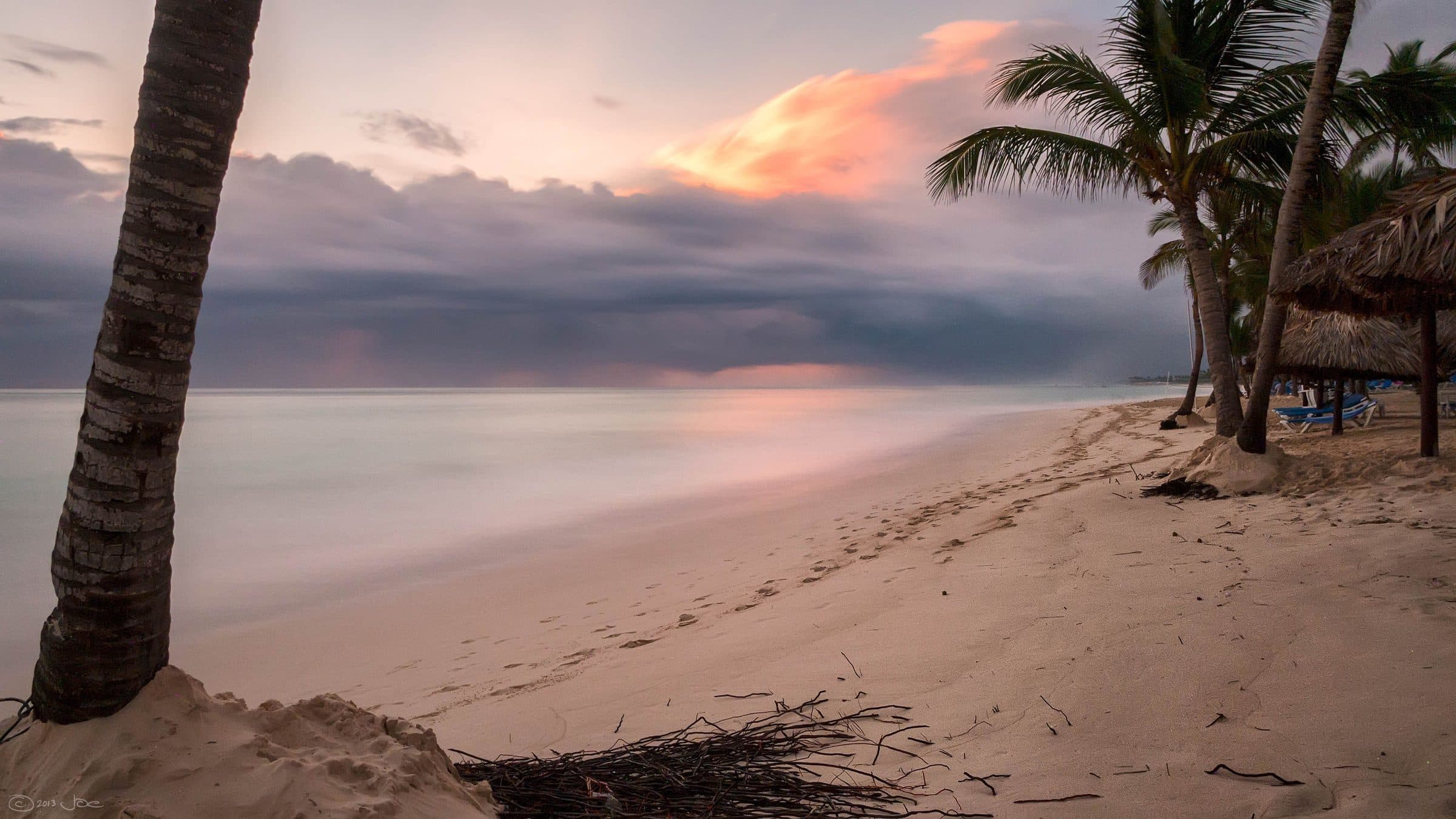 Praia em Punta Cana, na República Dominicana, com coqueiros durante o pôr do sol
