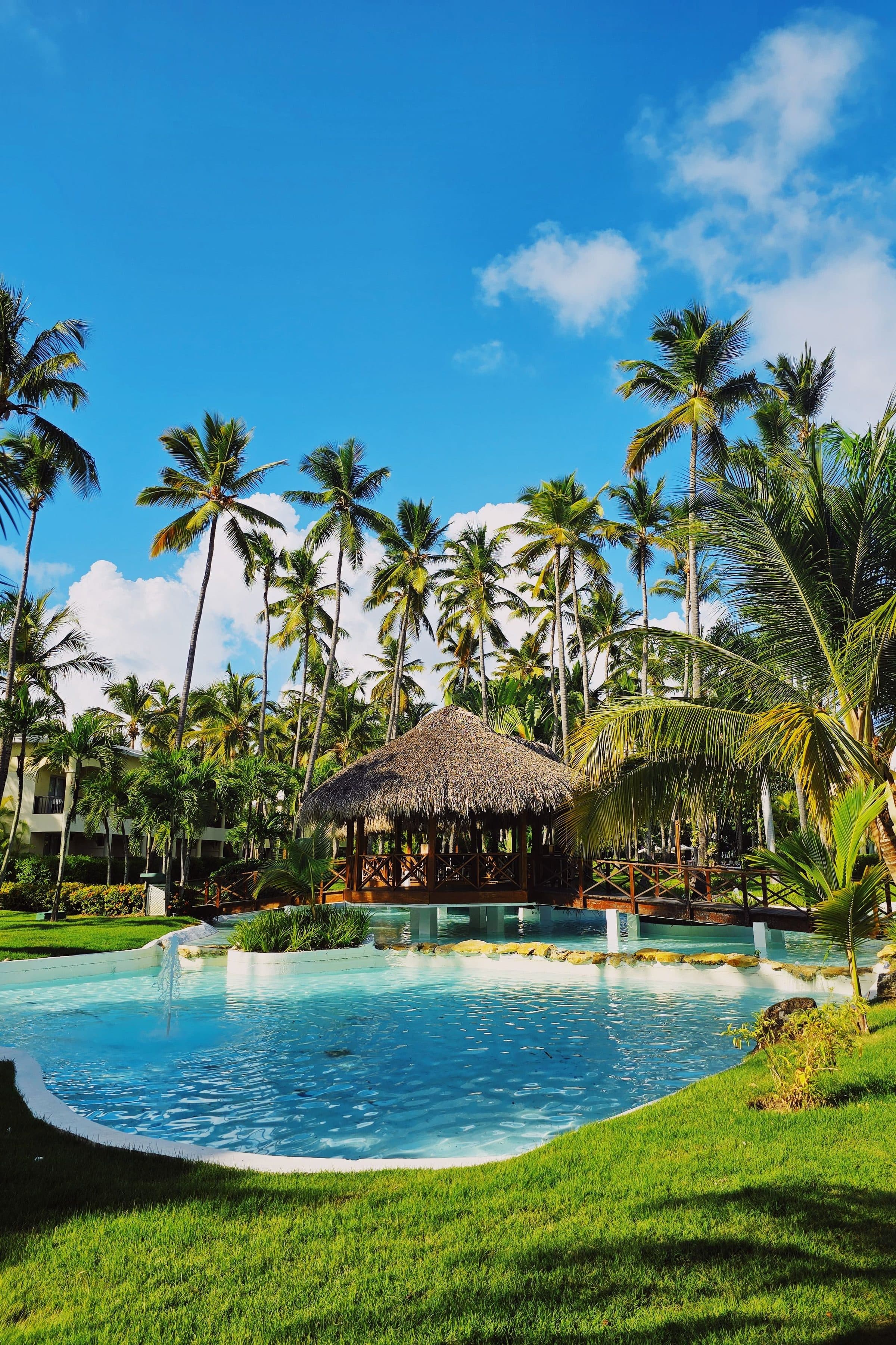 Piscina de águas azul-turquesa cercada por palmeiras em resort em Punta Cana