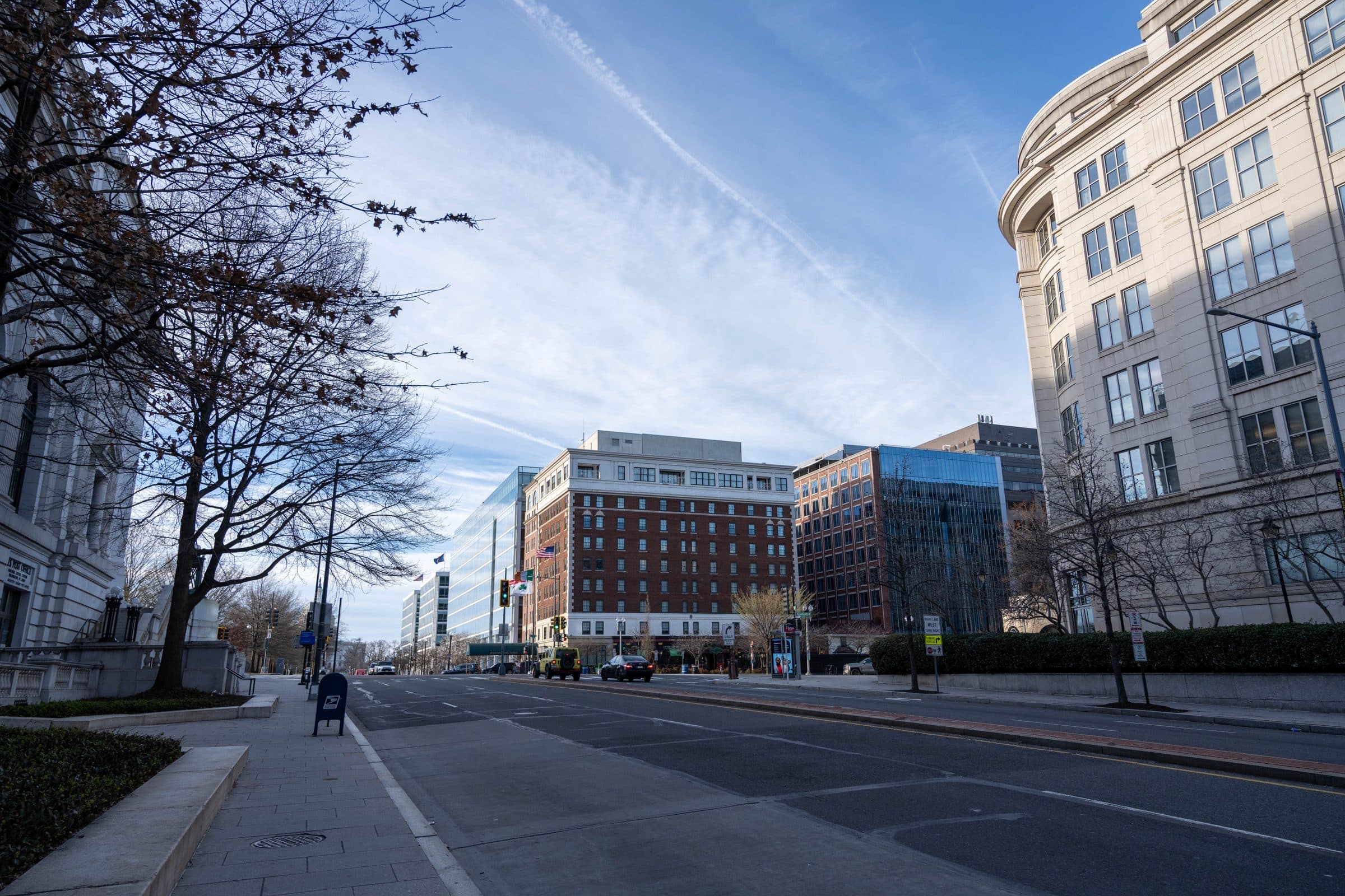 Rua em Washington, D.C. com prédios modernos e históricos sob céu limpo