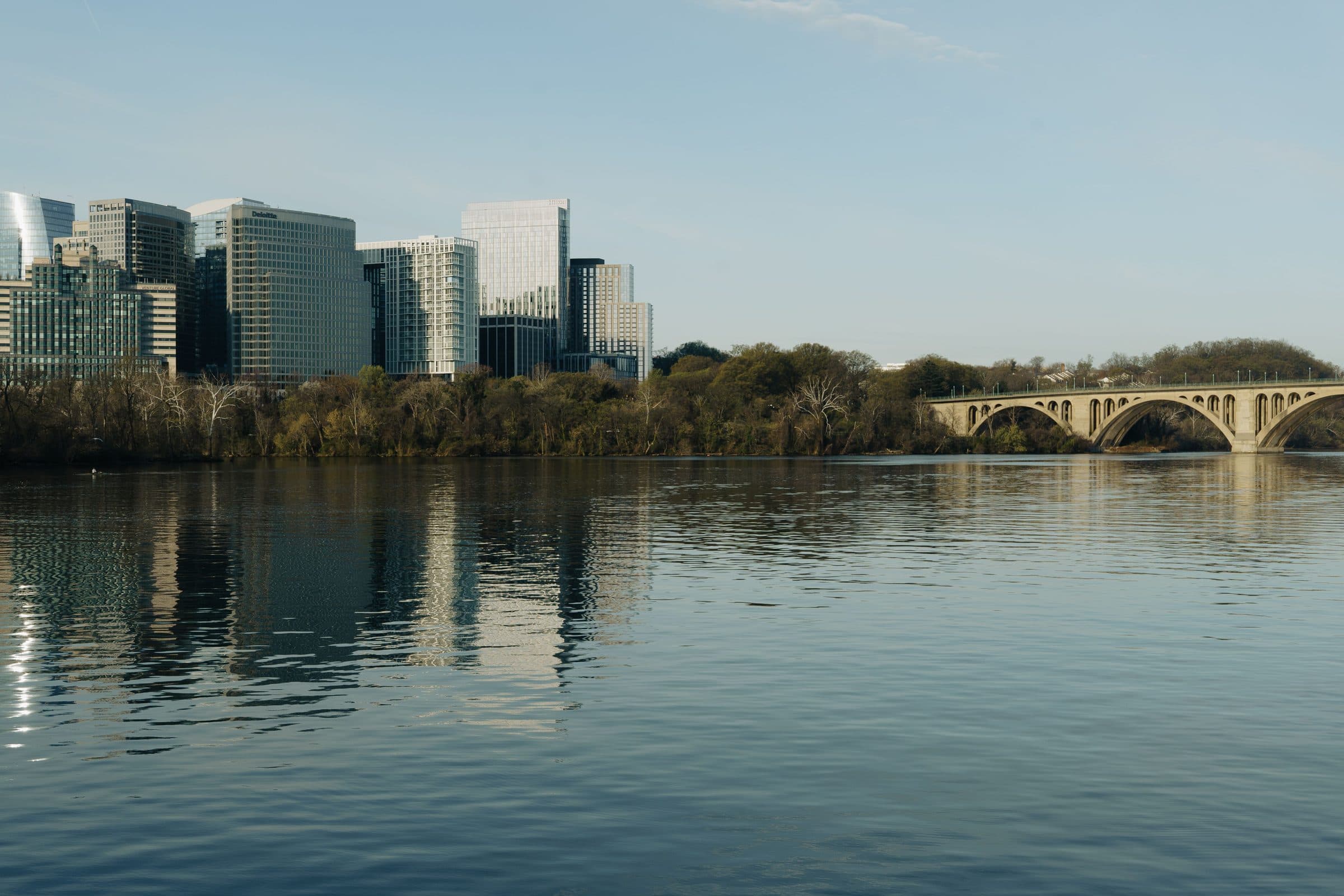 Edifícios urbanos e a Key Bridge refletidos nas águas do Rio Potomac