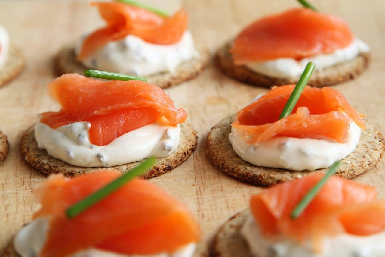 Canapés de salmão defumado servidos sobre biscoitos crocantes