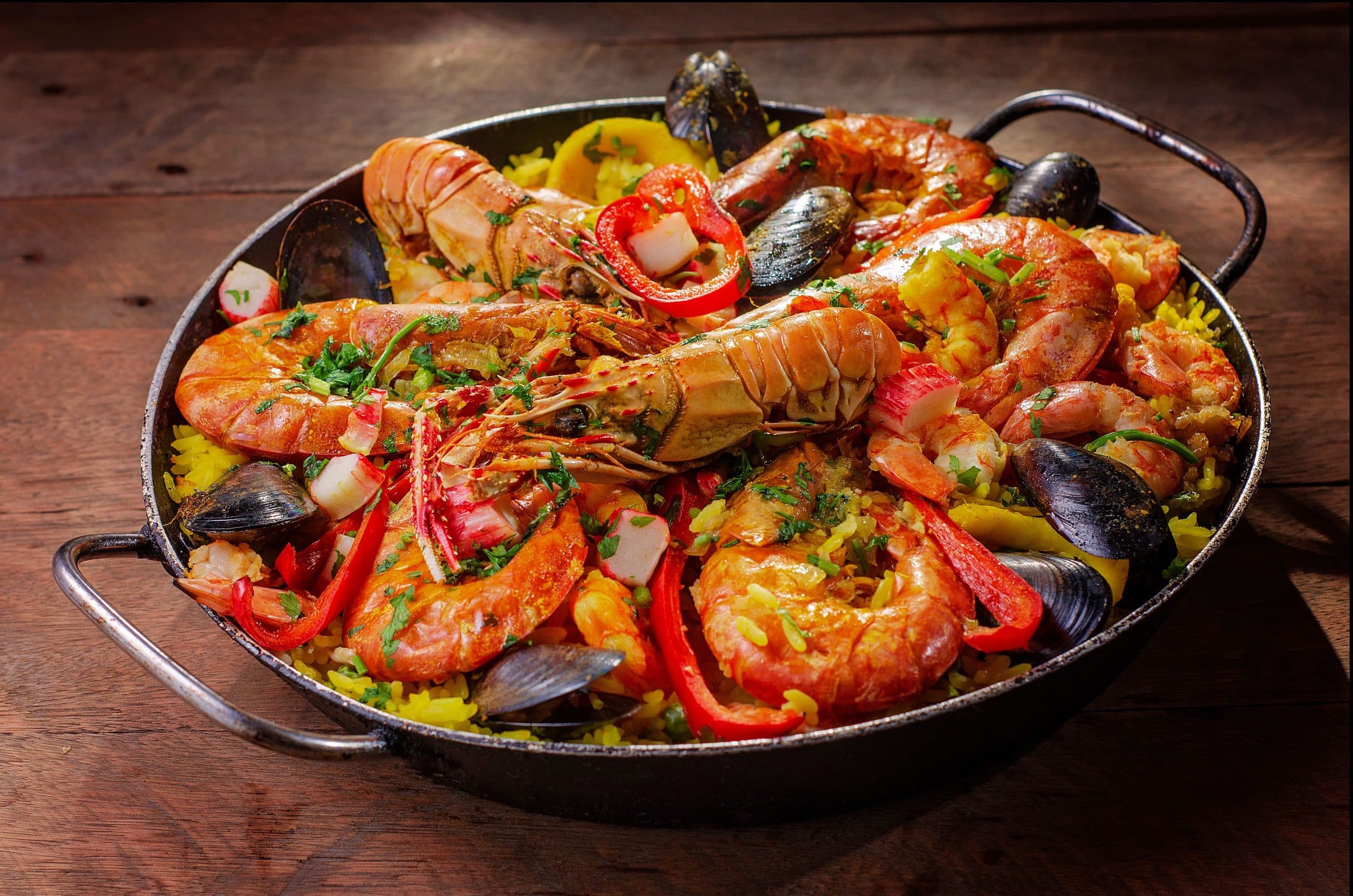 Paella de frutos do mar servida em uma panela com mexilhões e camarões