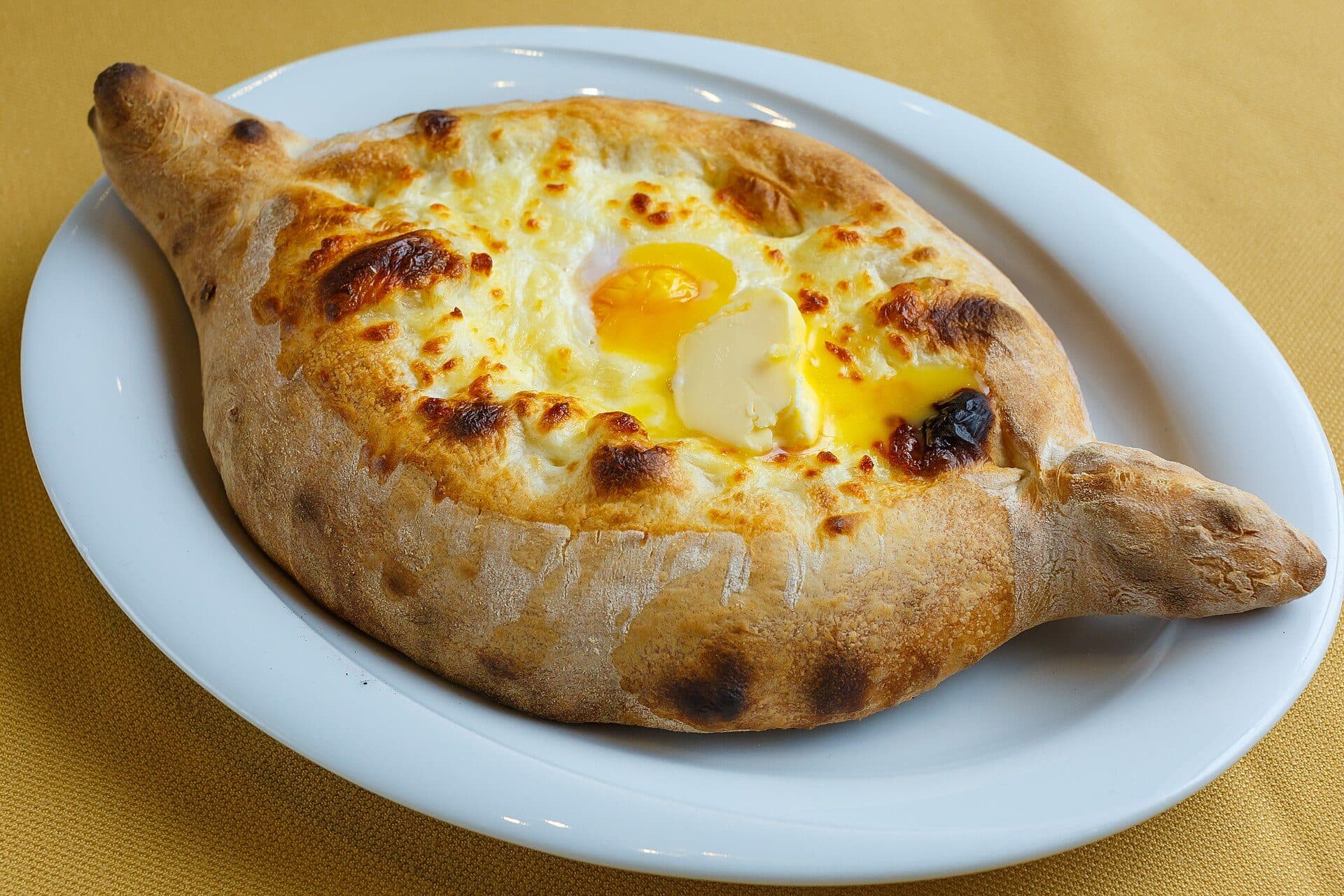 Khachapuri Adjaruli servido com gema de ovo e manteiga