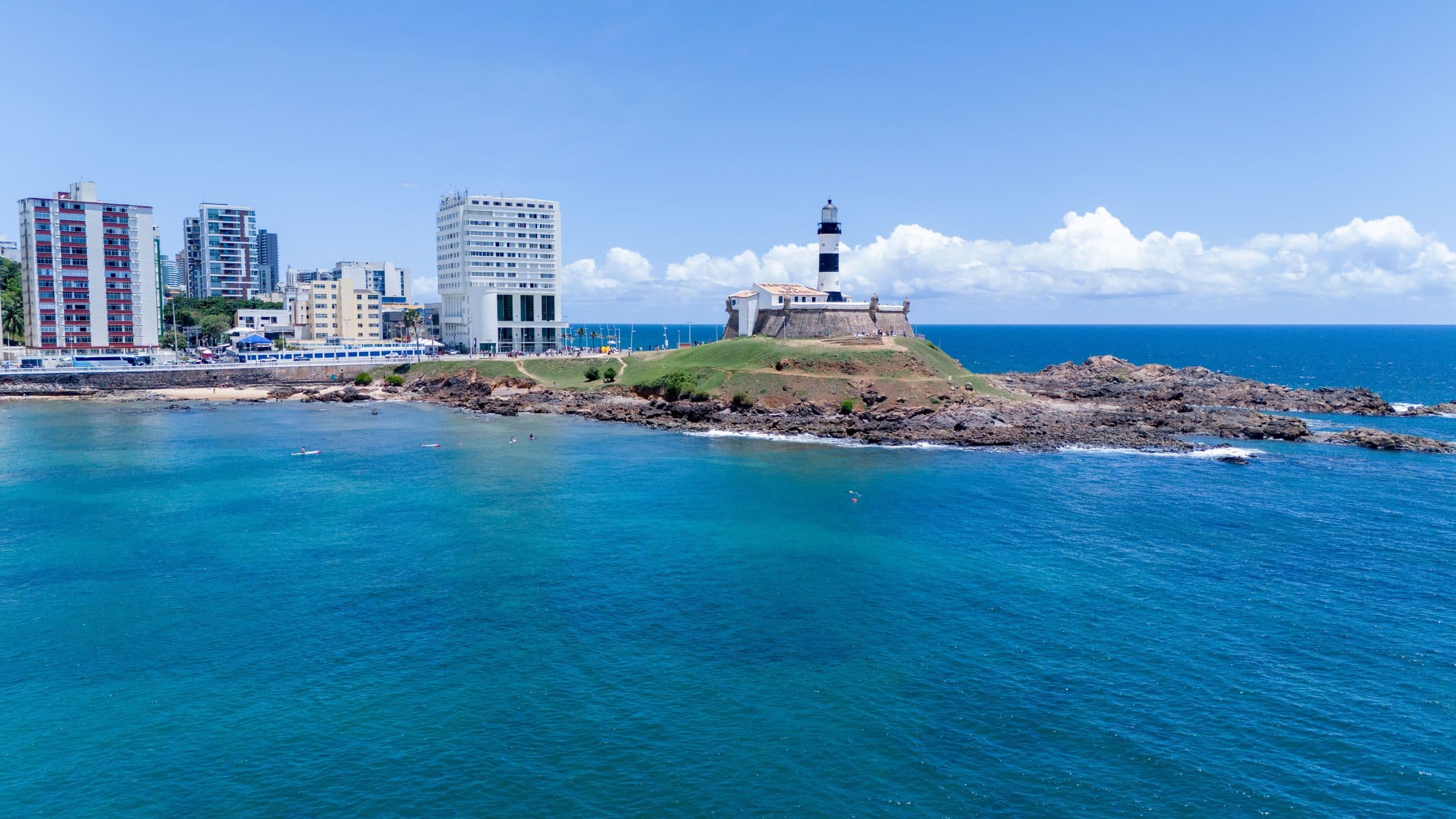 Vista aérea do Farol da Barra e orla costeira em dia ensolarado em Salvador