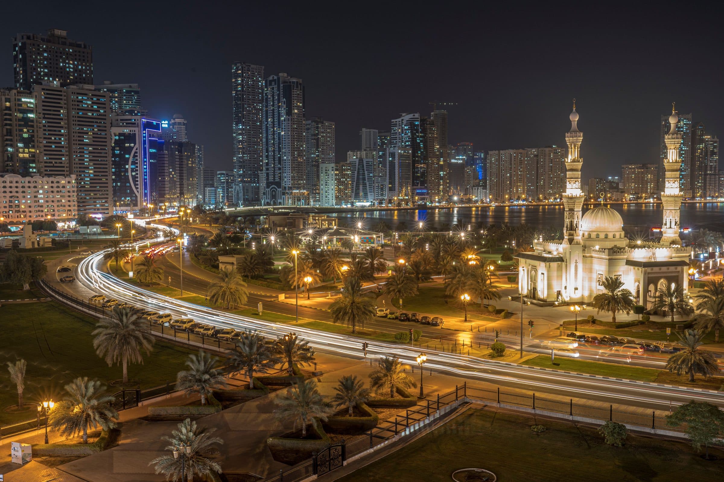 Vista aérea noturna de Sharjah com destaque para a Mesquita Al Noor e luzes da cidade