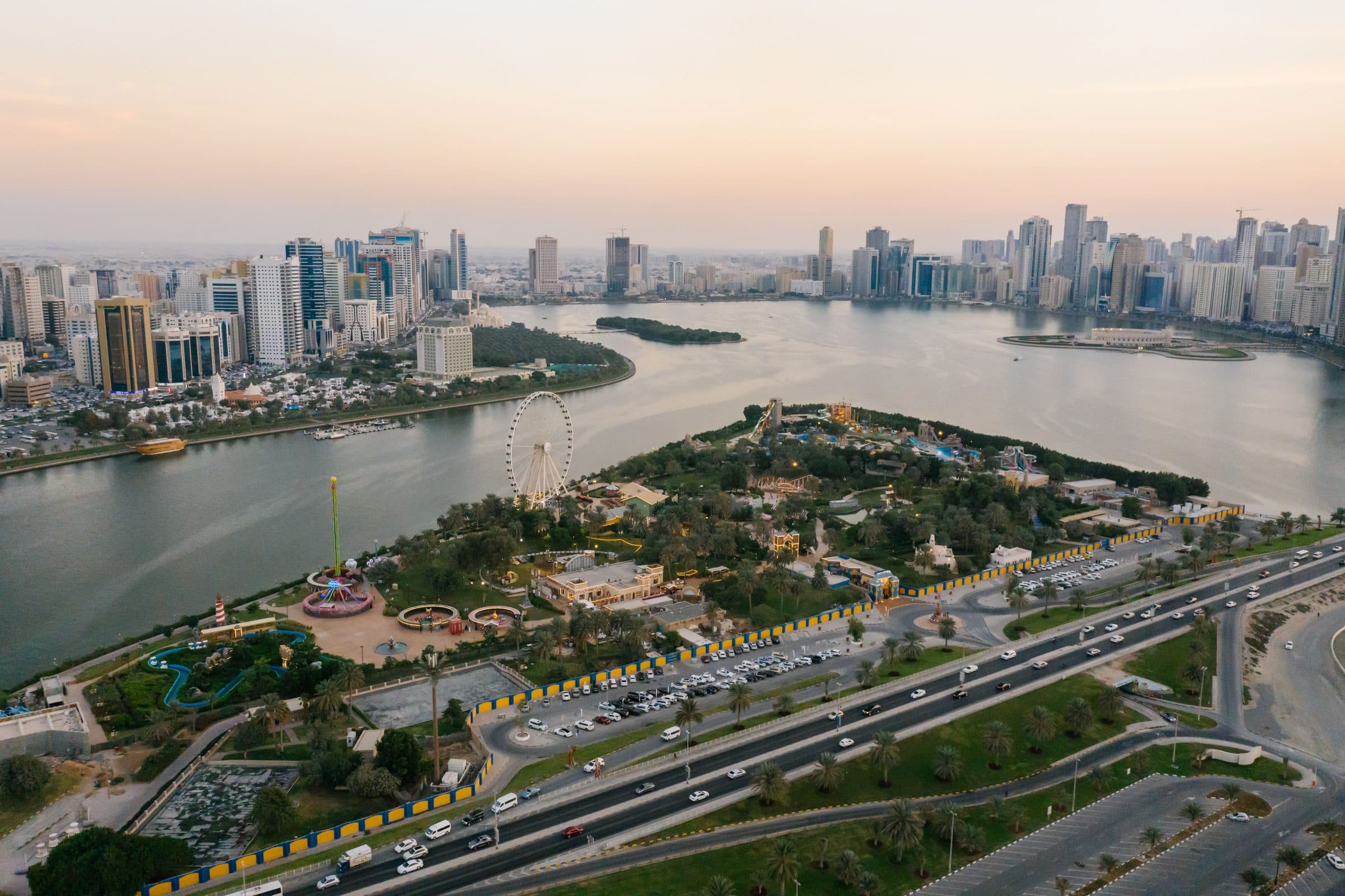 Vista aérea da cidade de Sharjah com parques, monumentos e litoral ao pôr do sol
