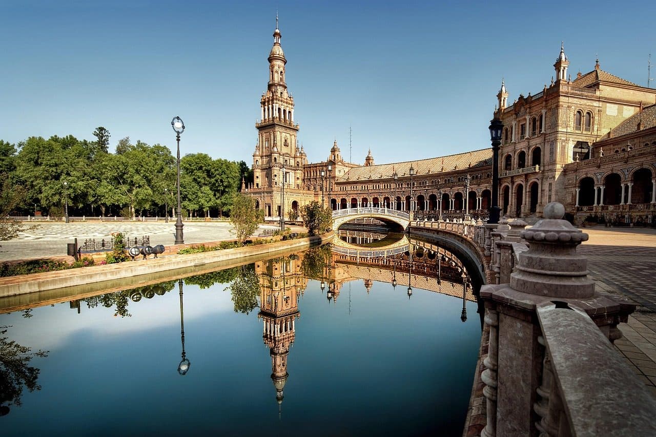 Palácio com torre refletido em espelho d'água em Sevilha, Espanha