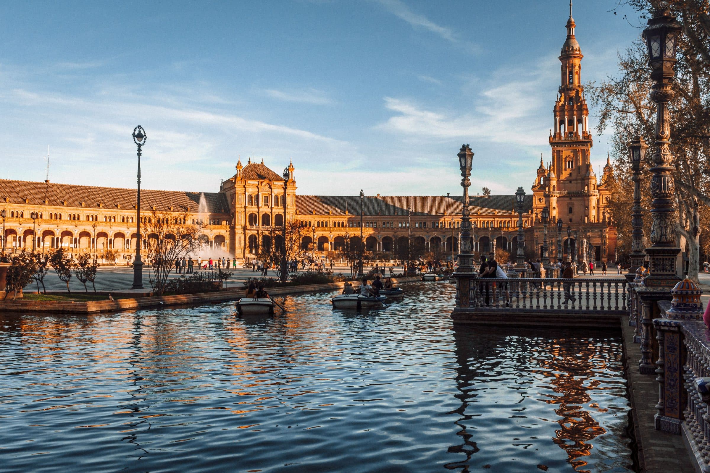Vista da Plaza de España em Sevilha com reflexos no canal ao pôr do sol