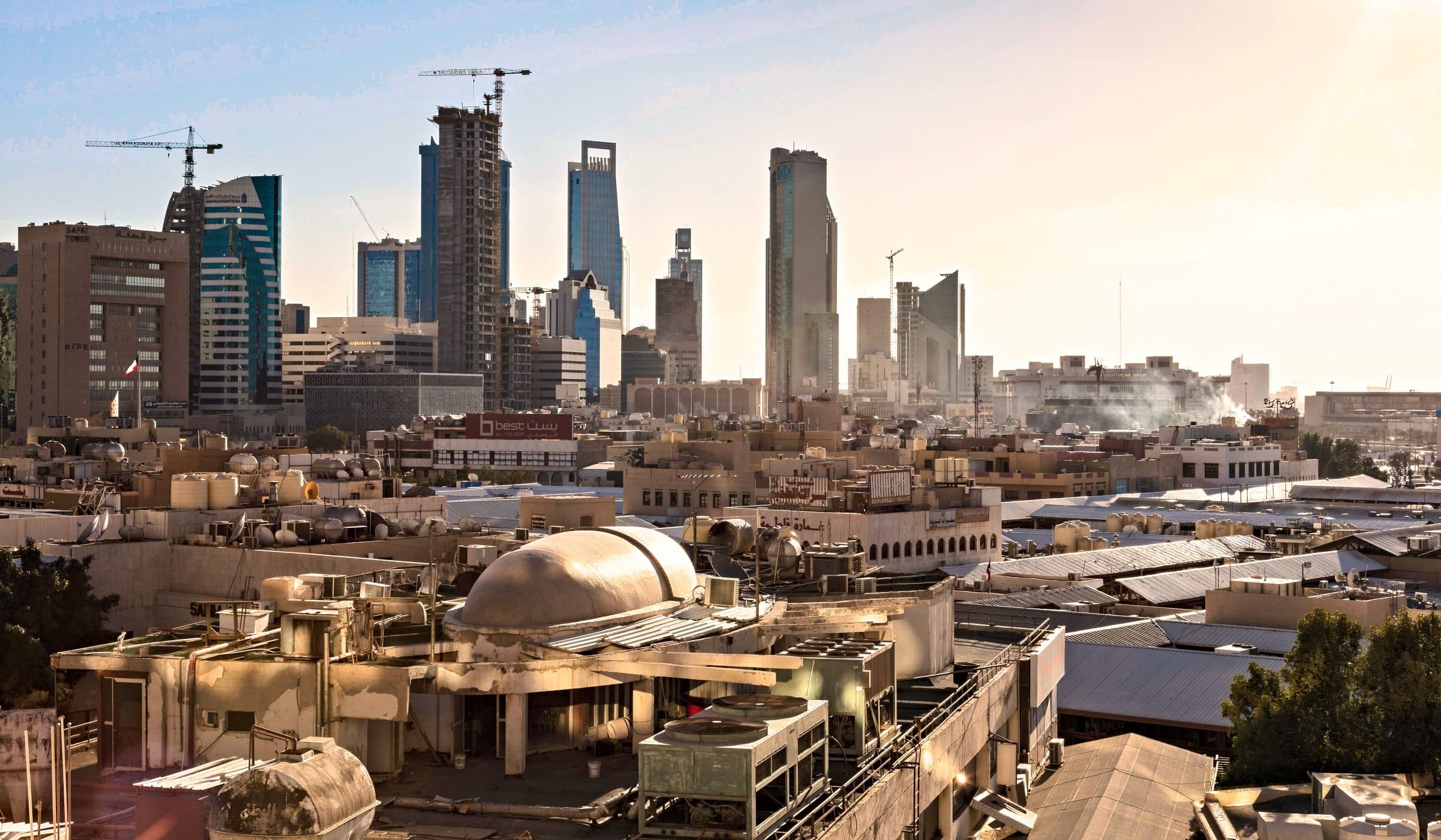 Skyline de Riad com arranha-céus modernos e guindastes de construção ao pôr do sol