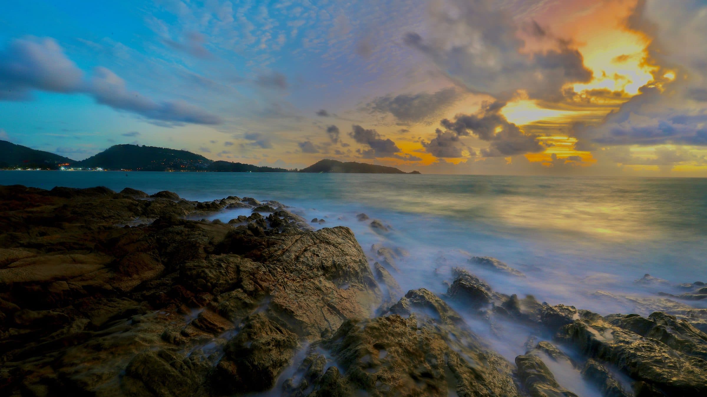 Pôr do sol sobre a costa rochosa em Patong Beach, Phuket, Tailândia