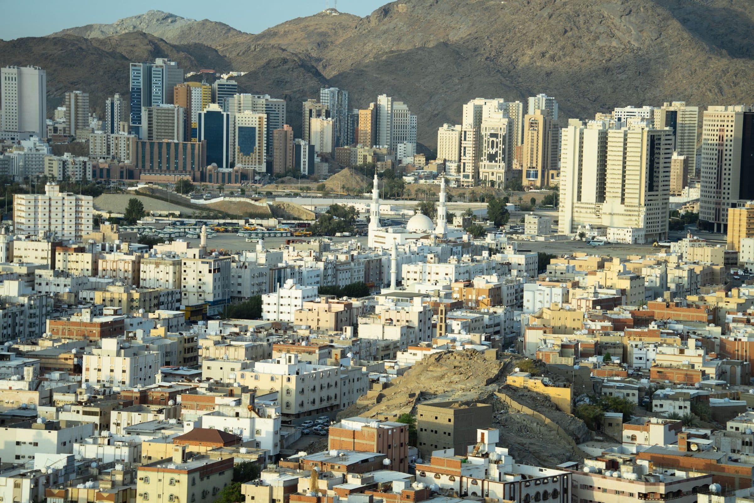 Vista aérea diurna da cidade de Makkah com arranha-céus modernos e montanhas ao redor
