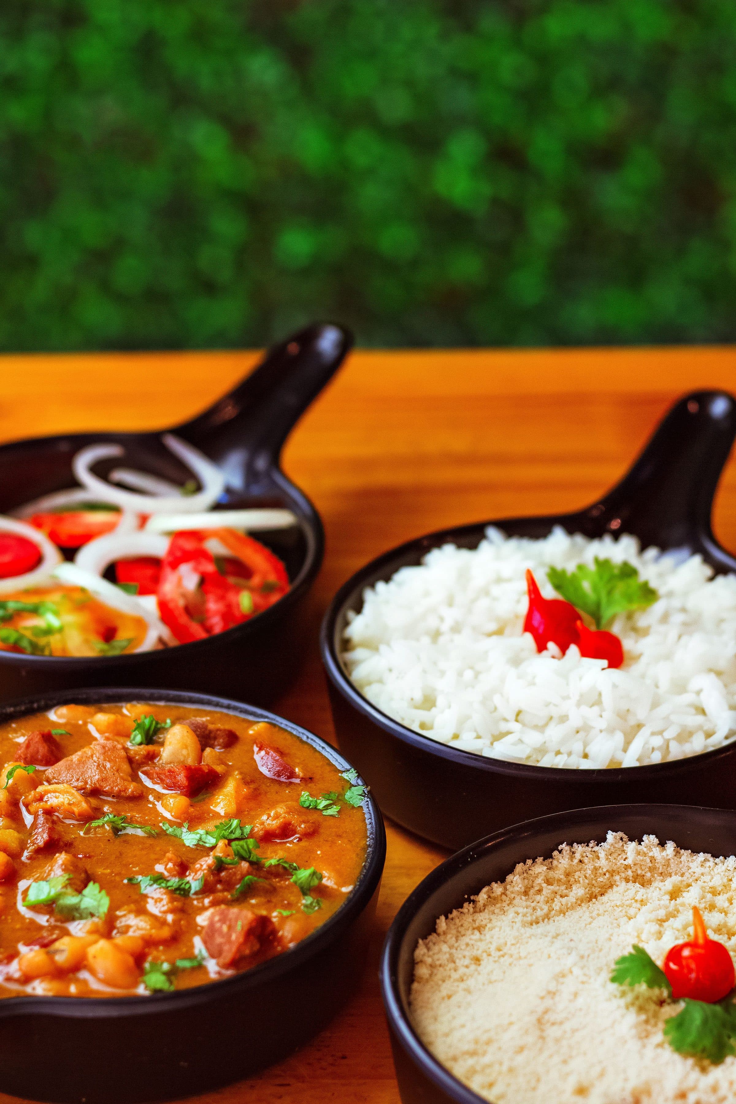 Pratos da culinária brasileira com arroz, feijão e legumes servidos sobre uma mesa de madeira