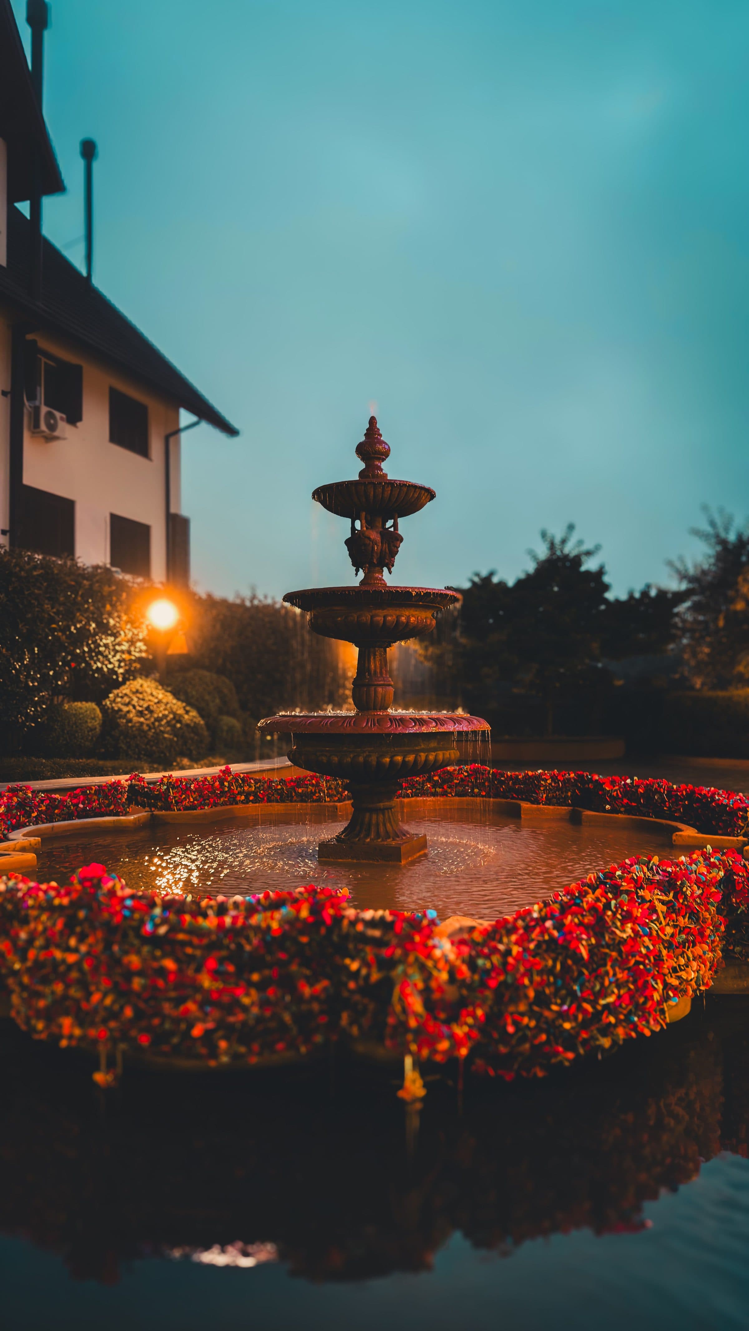 Fonte cercada por flores coloridas durante o entardecer em Gramado