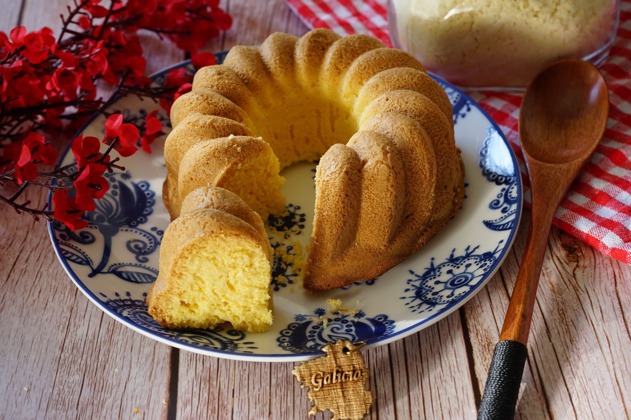 Bolo bundt caseiro com flores vermelhas sobre fundo de madeira