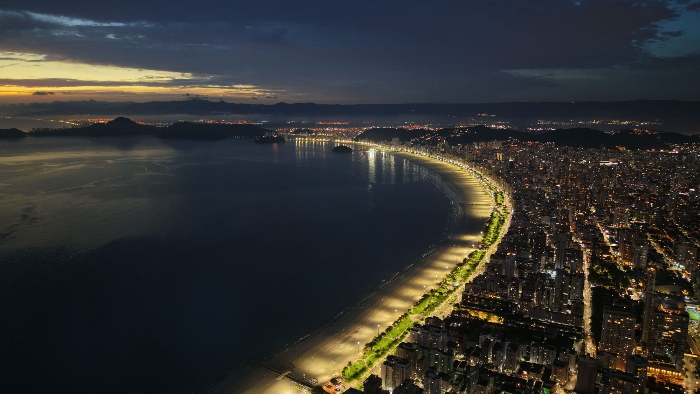 Vista aérea noturna da orla iluminada da praia de Santos em São Paulo