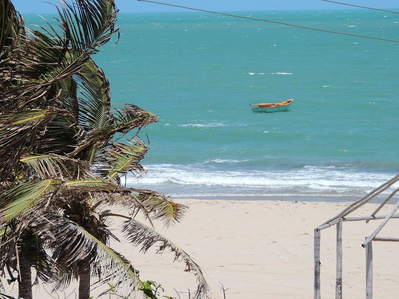Praia no litoral do Piauí com coqueiros e um barco no mar