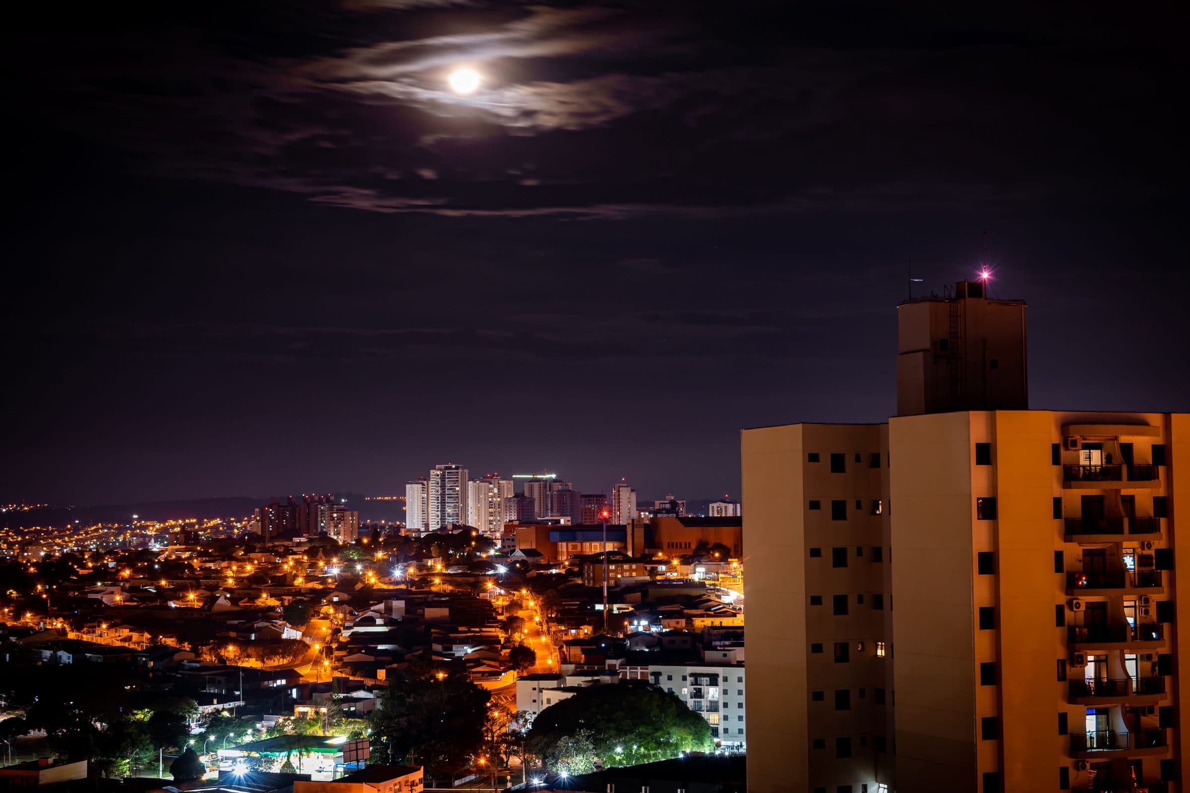 Vista aérea noturna da cidade de Campinas iluminada sob a lua cheia