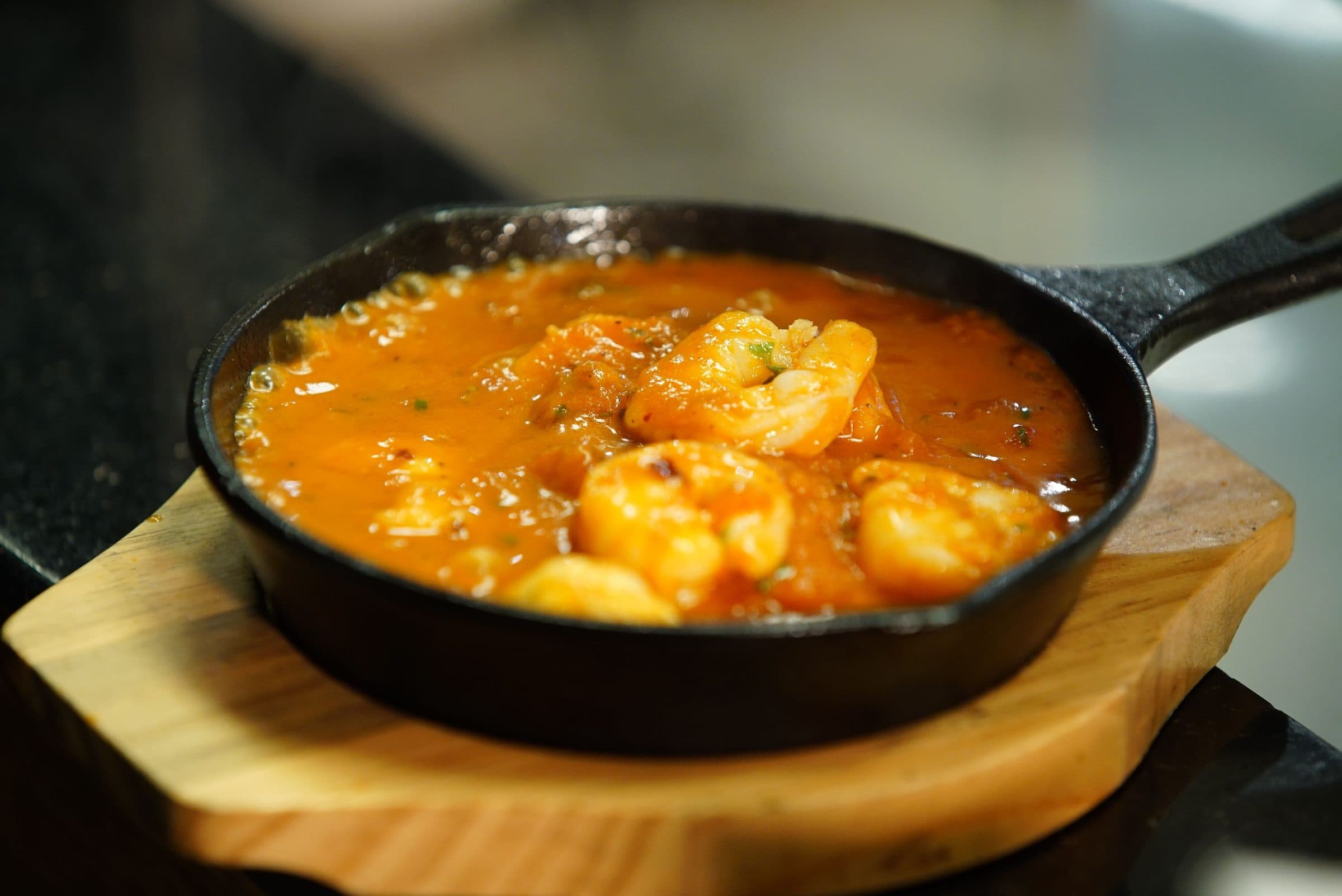 Camarões cozinhando em molho de tomate em uma frigideira de ferro fundido
