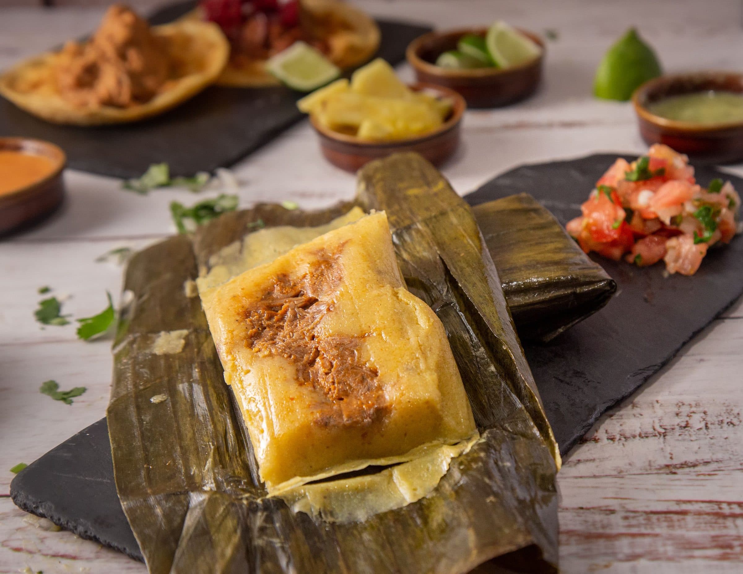 Tamale mexicano servido com molho sobre uma mesa rústica de madeira
