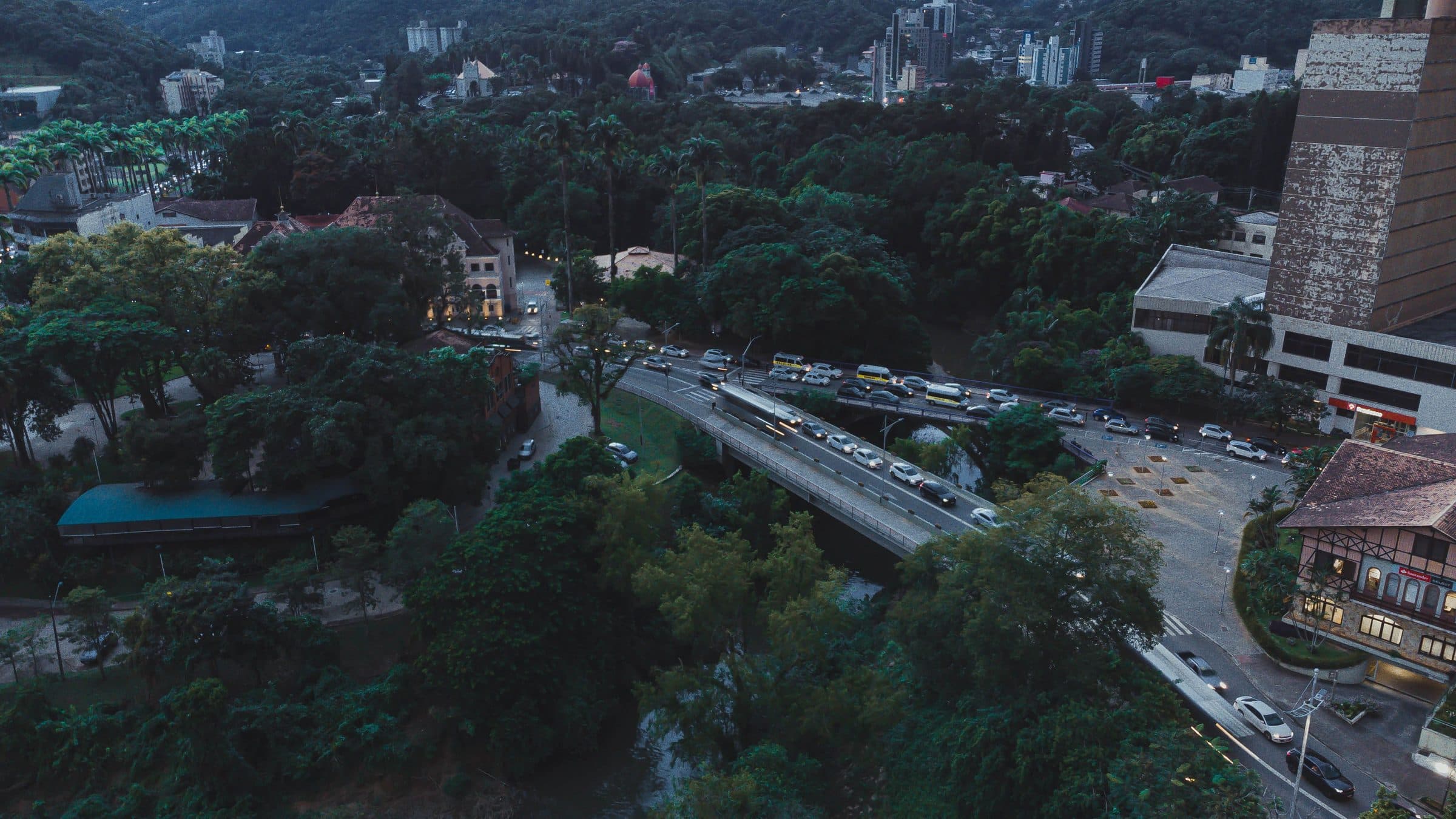 Vista aérea de rua movimentada cercada por vegetação em Blumenau ao entardecer